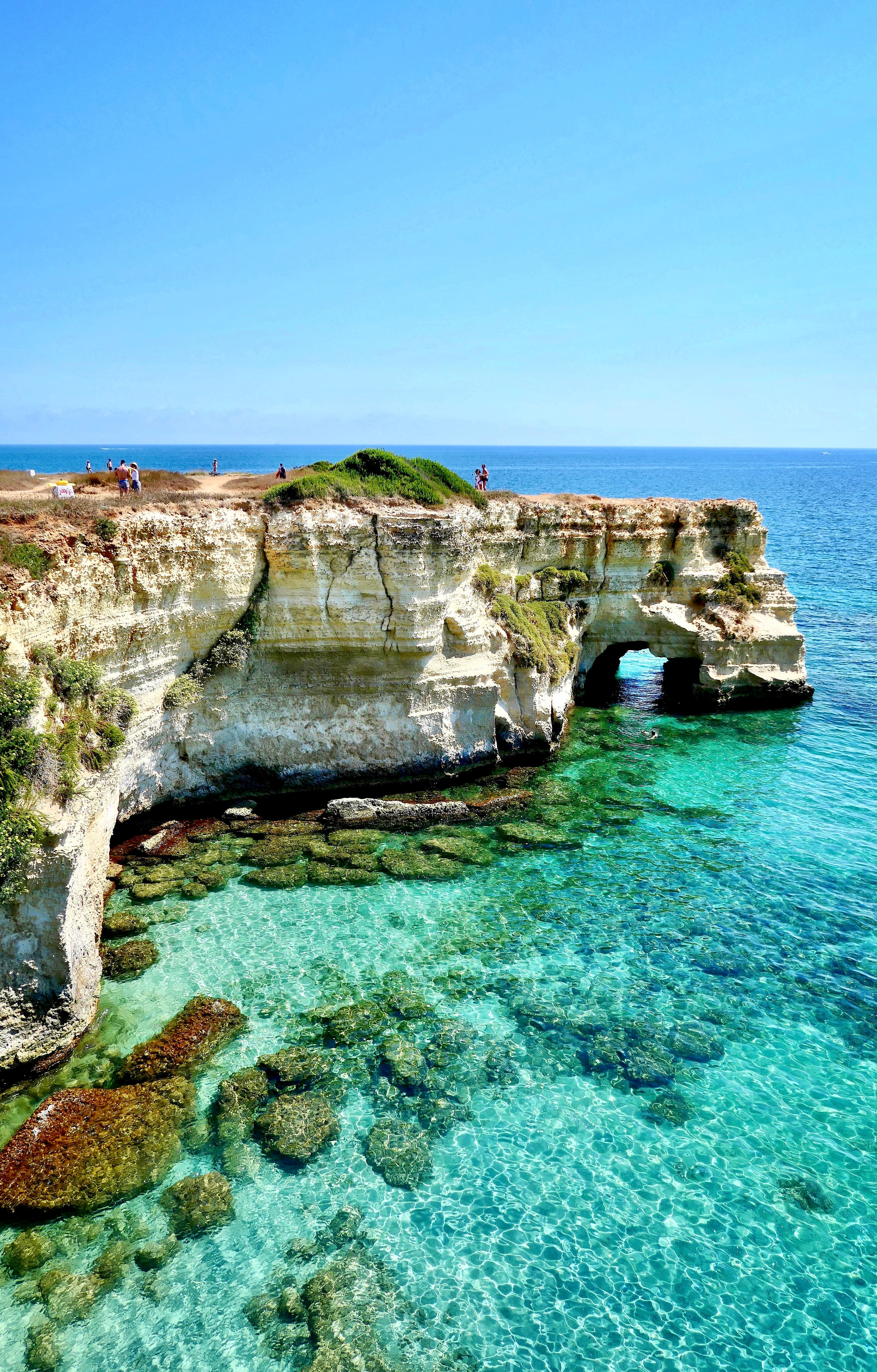 Puglia aerial coastal views with blue waters and rugged rocks.