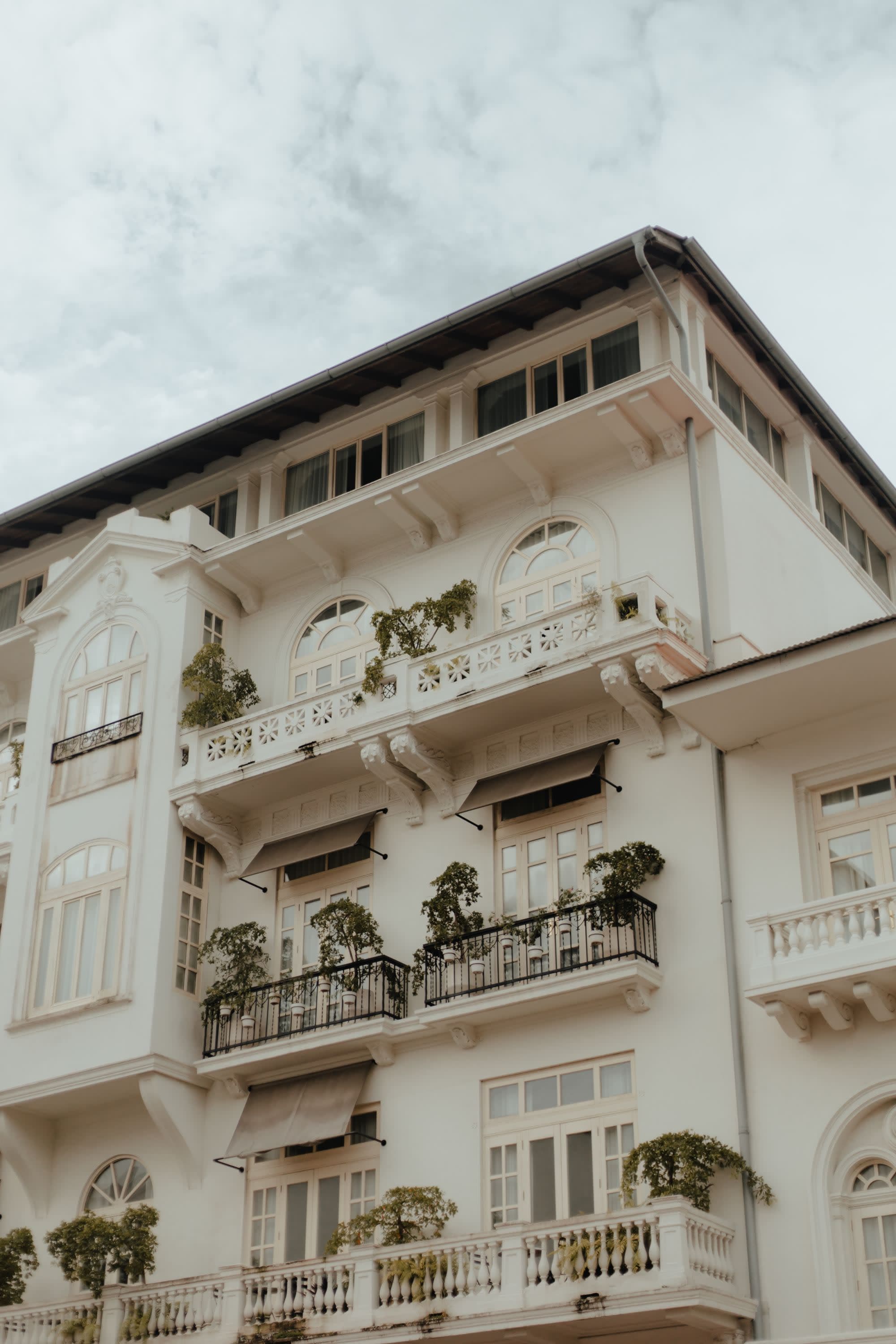 white historic building with small balconies against gray cloudy sky