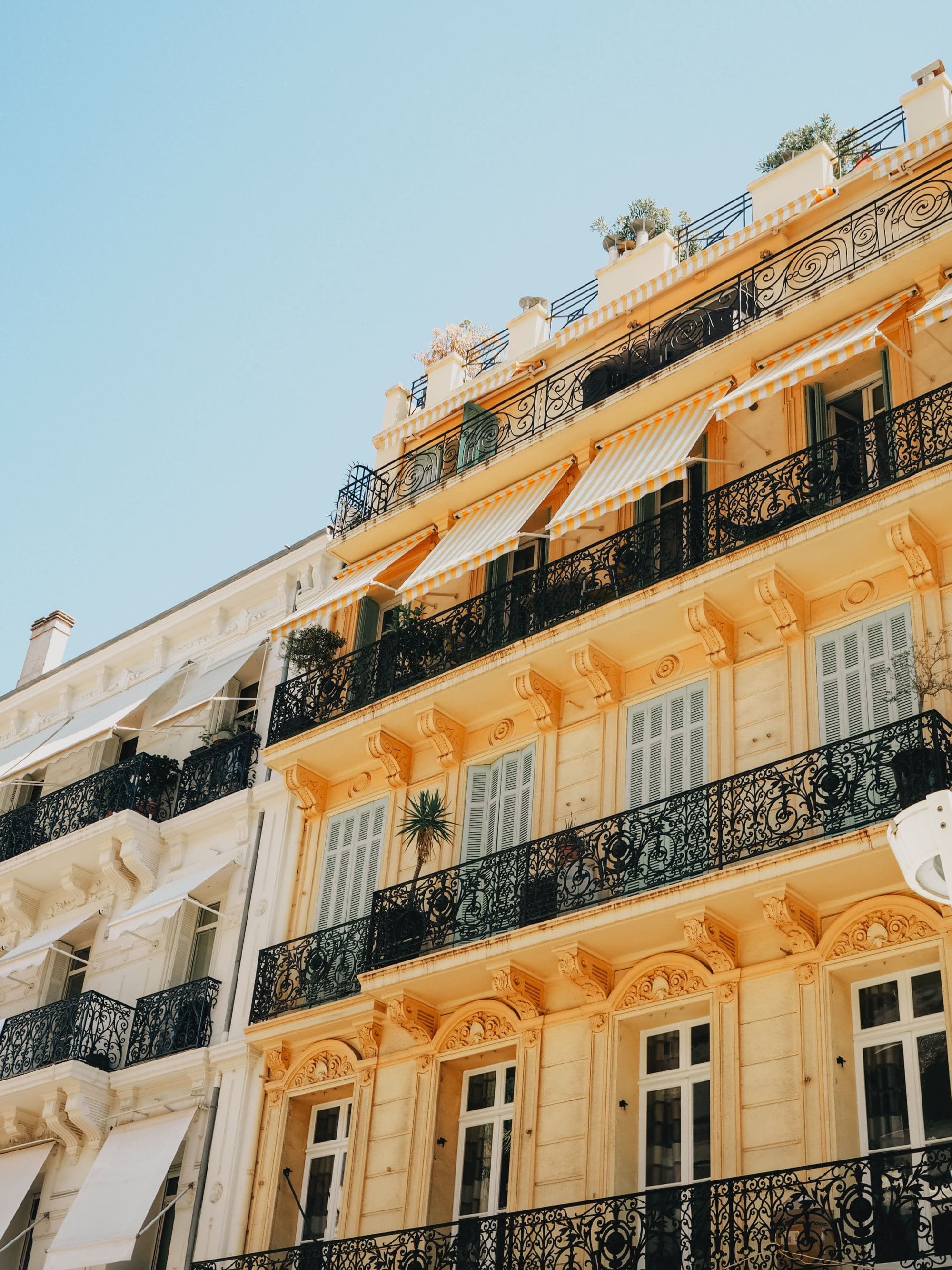 low-angle view of a yellow building with iron iron fences near the windows