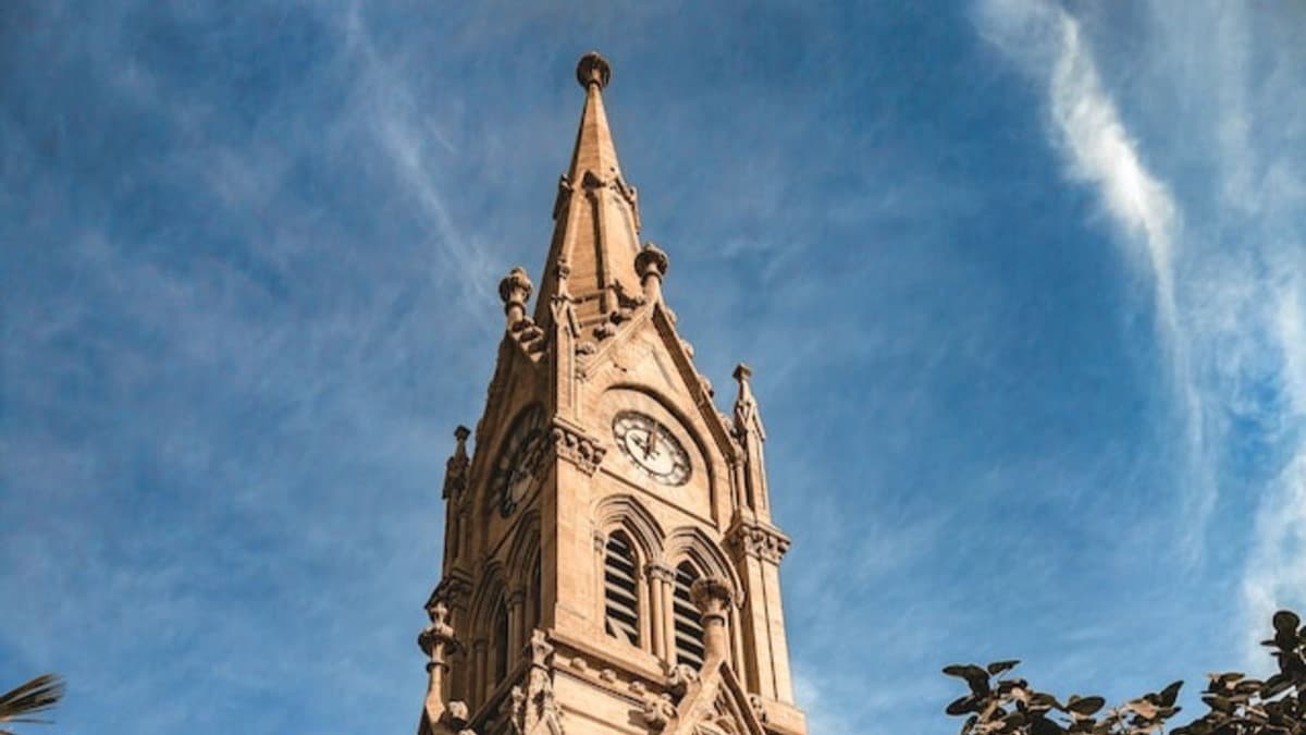 Large brown clocktower building under blue sky