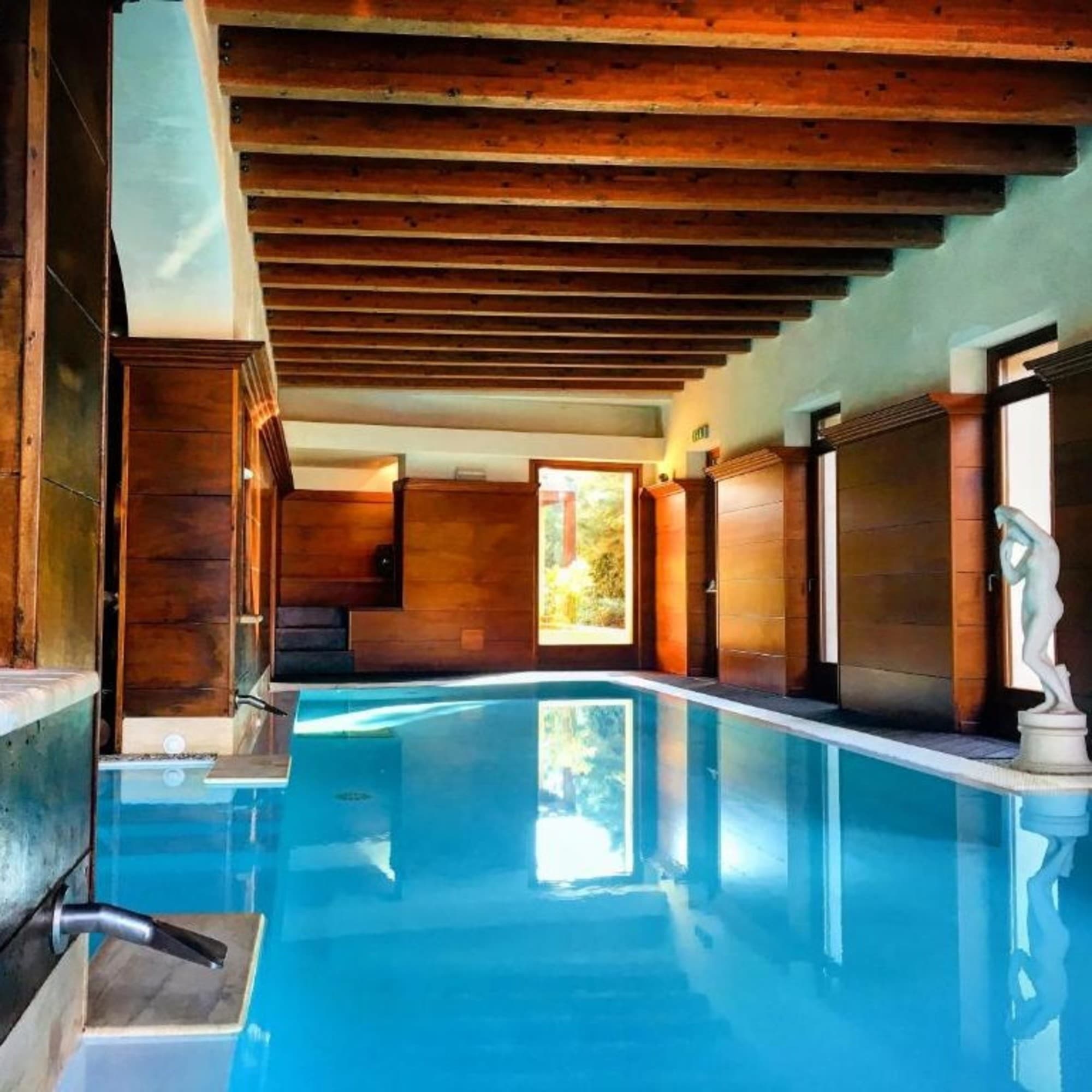 A picture of an indoor pool with wooden ceiling and walls.