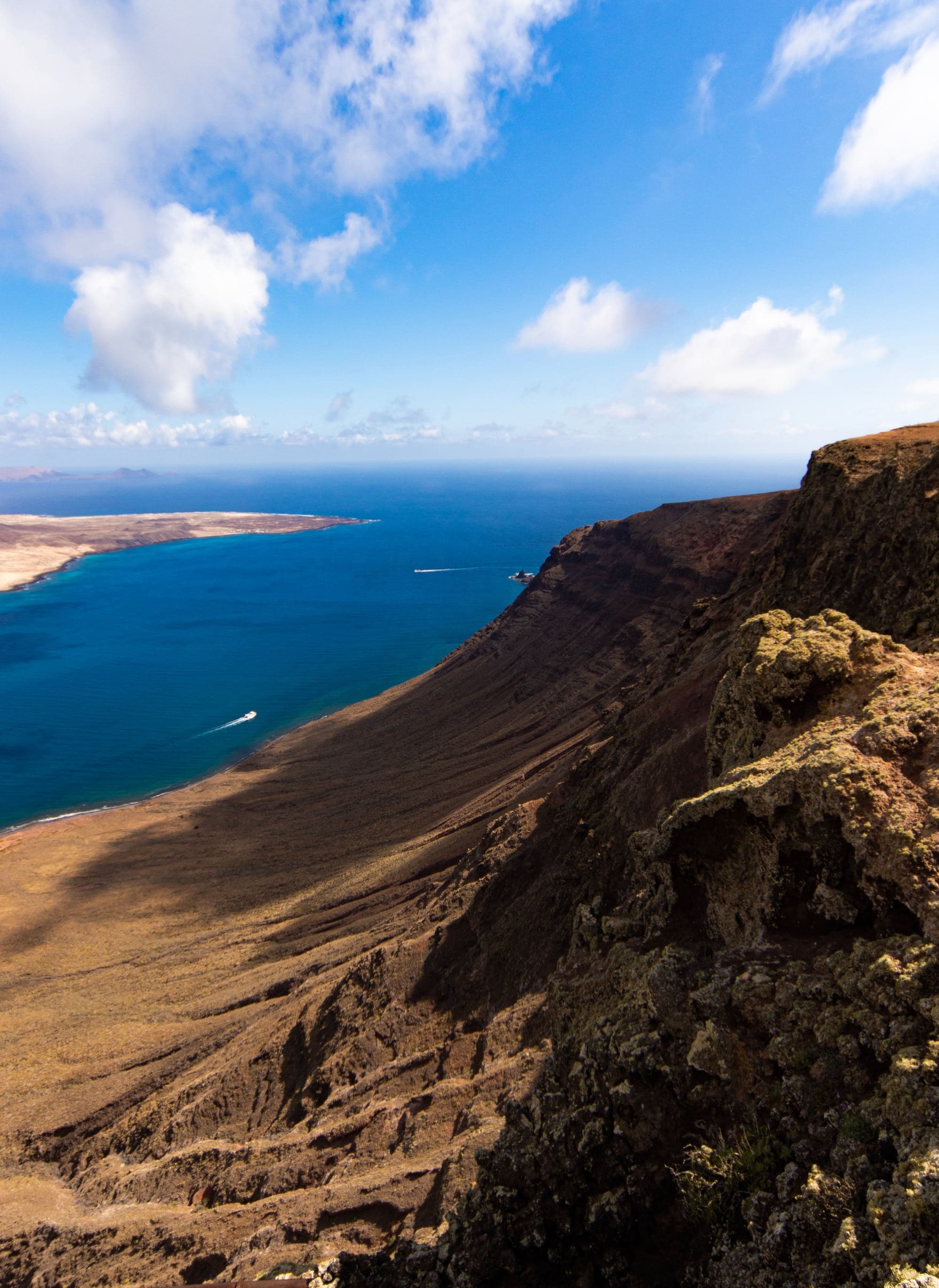 sloping sand cliffs into deep blue water and blue sky