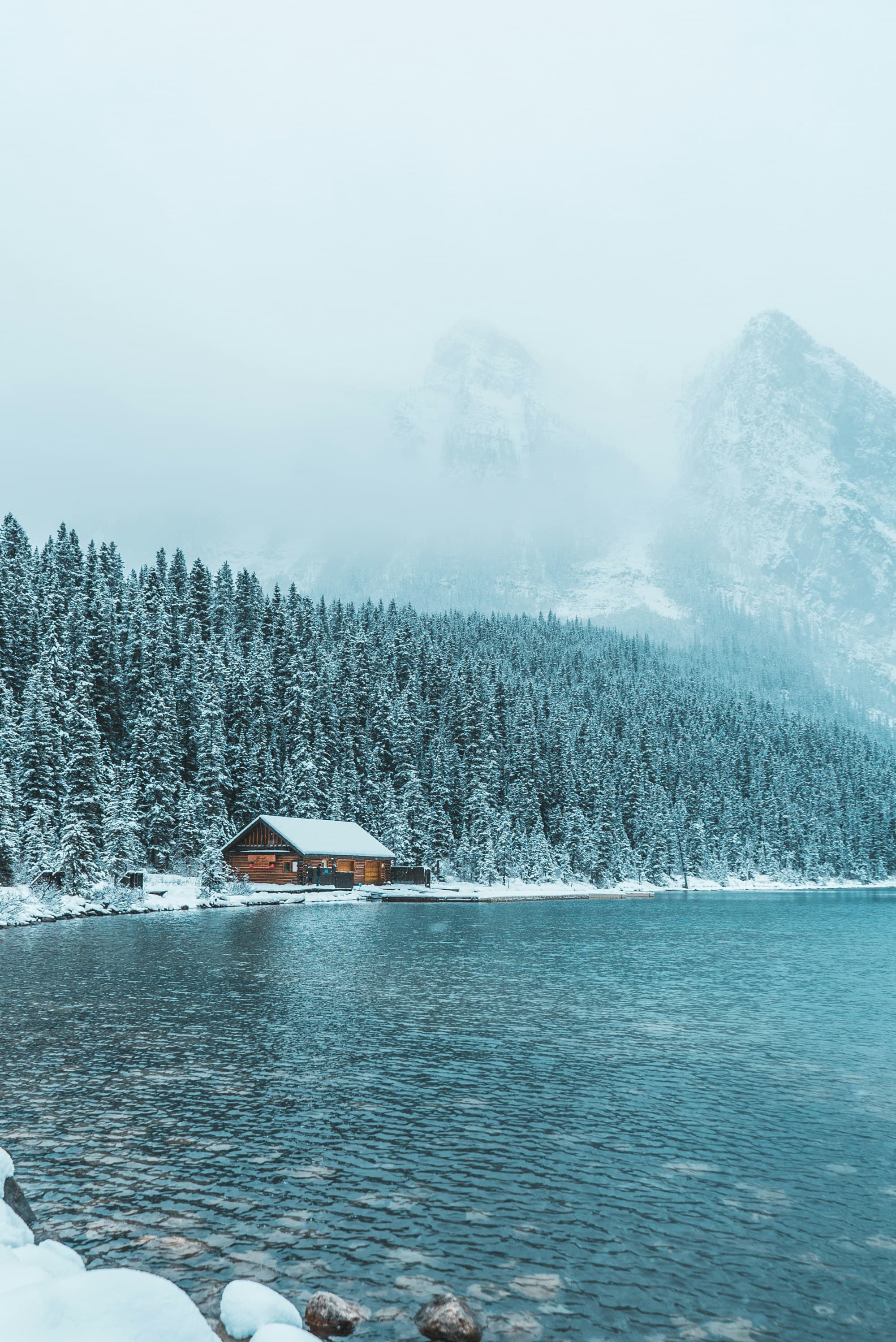 A brown wooden house near the water during daytime in the winter.