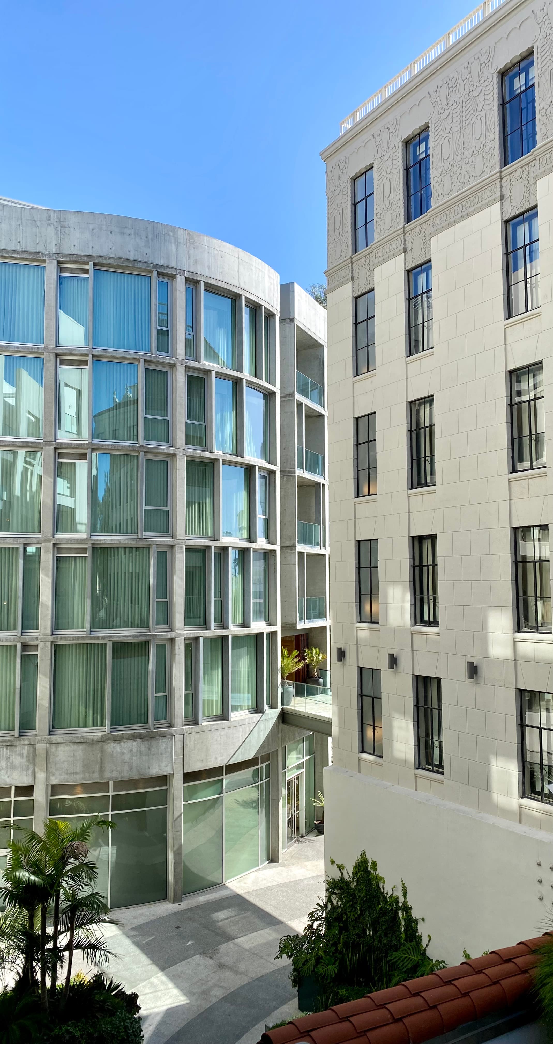A view of white building exteriors with green trees on the ground.
