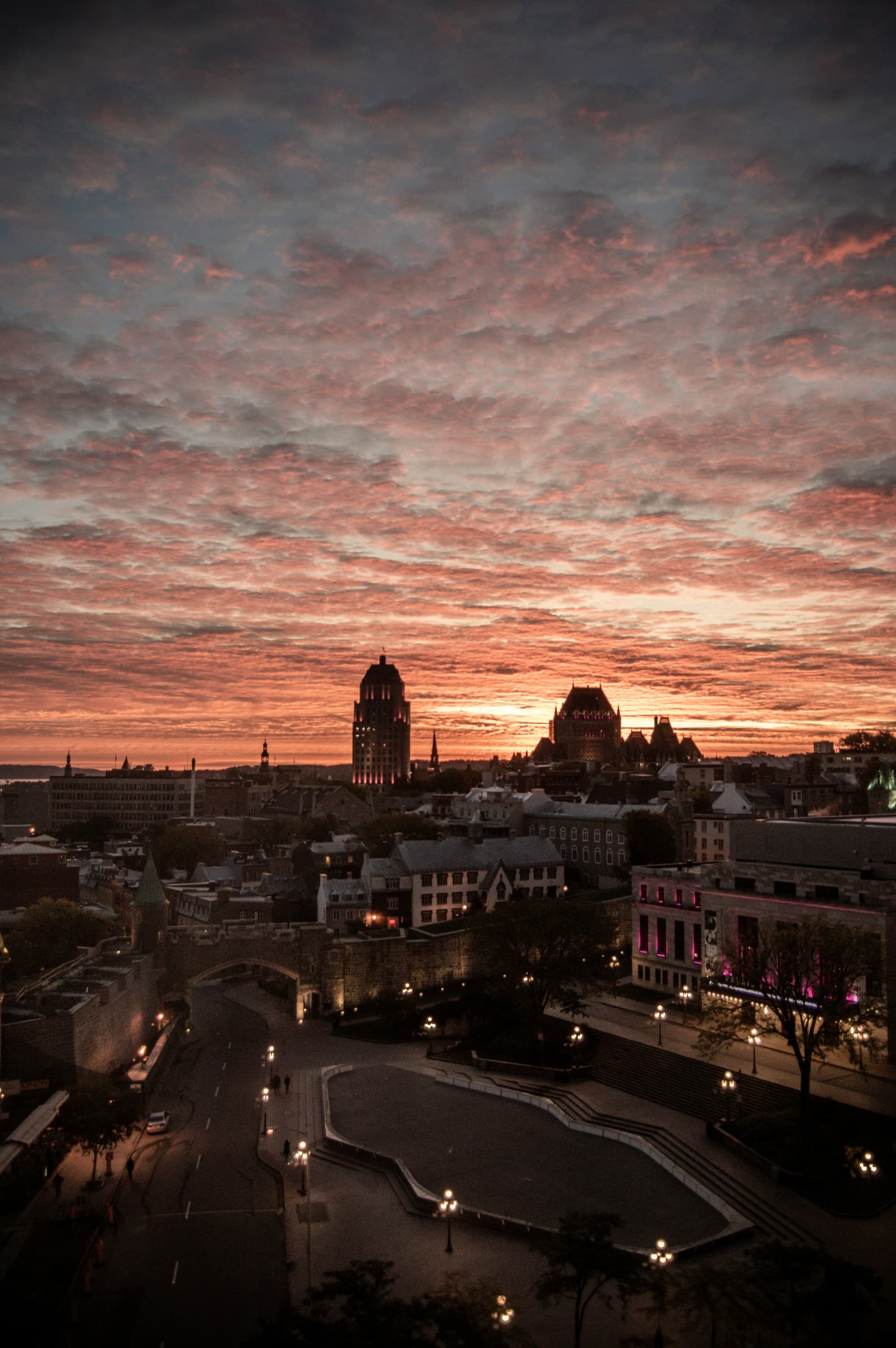 An aerial view of the city buildings under cloudy sky during the sunset.