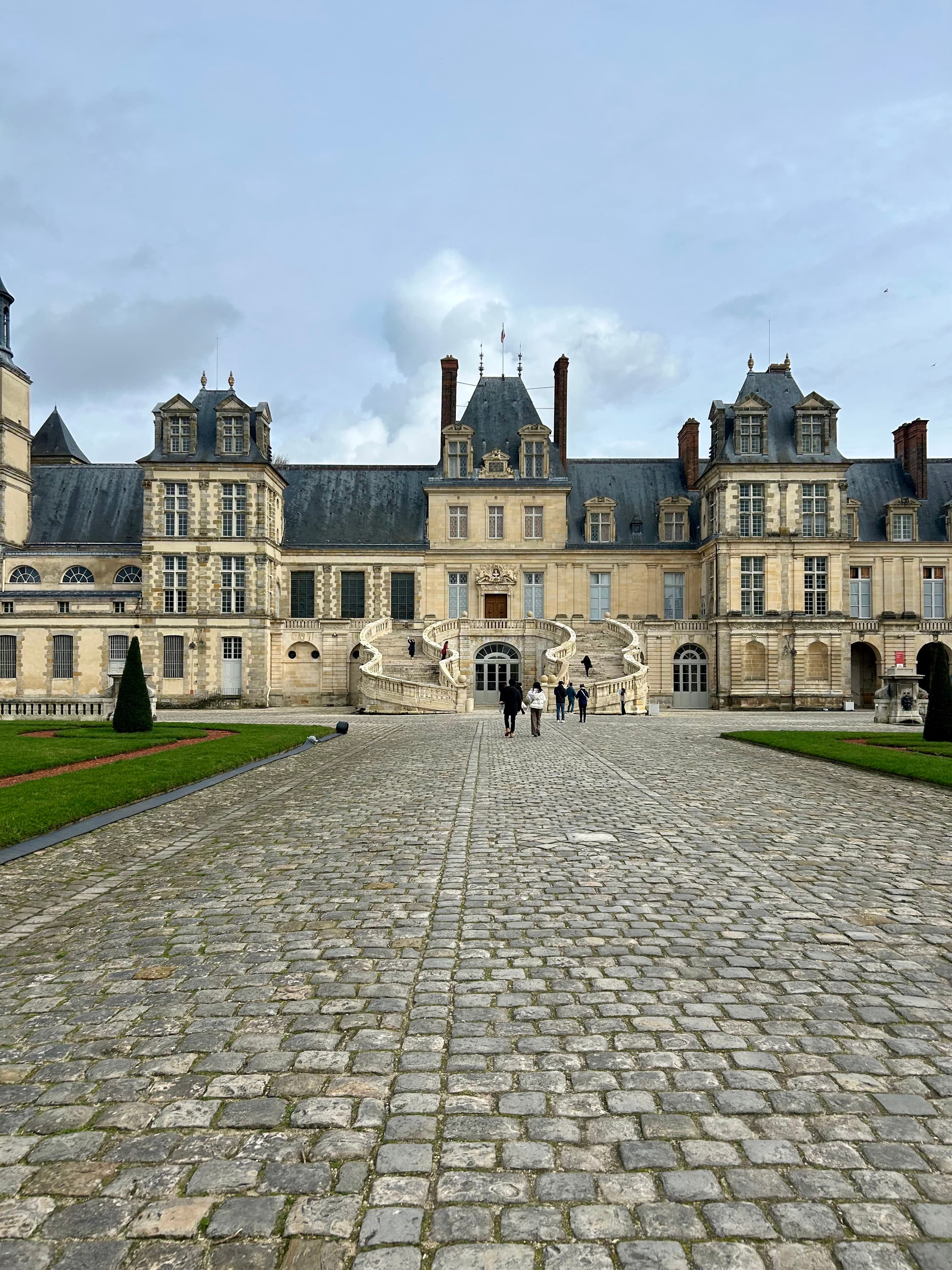 A brick pathway leading to a large castle during the daytime
