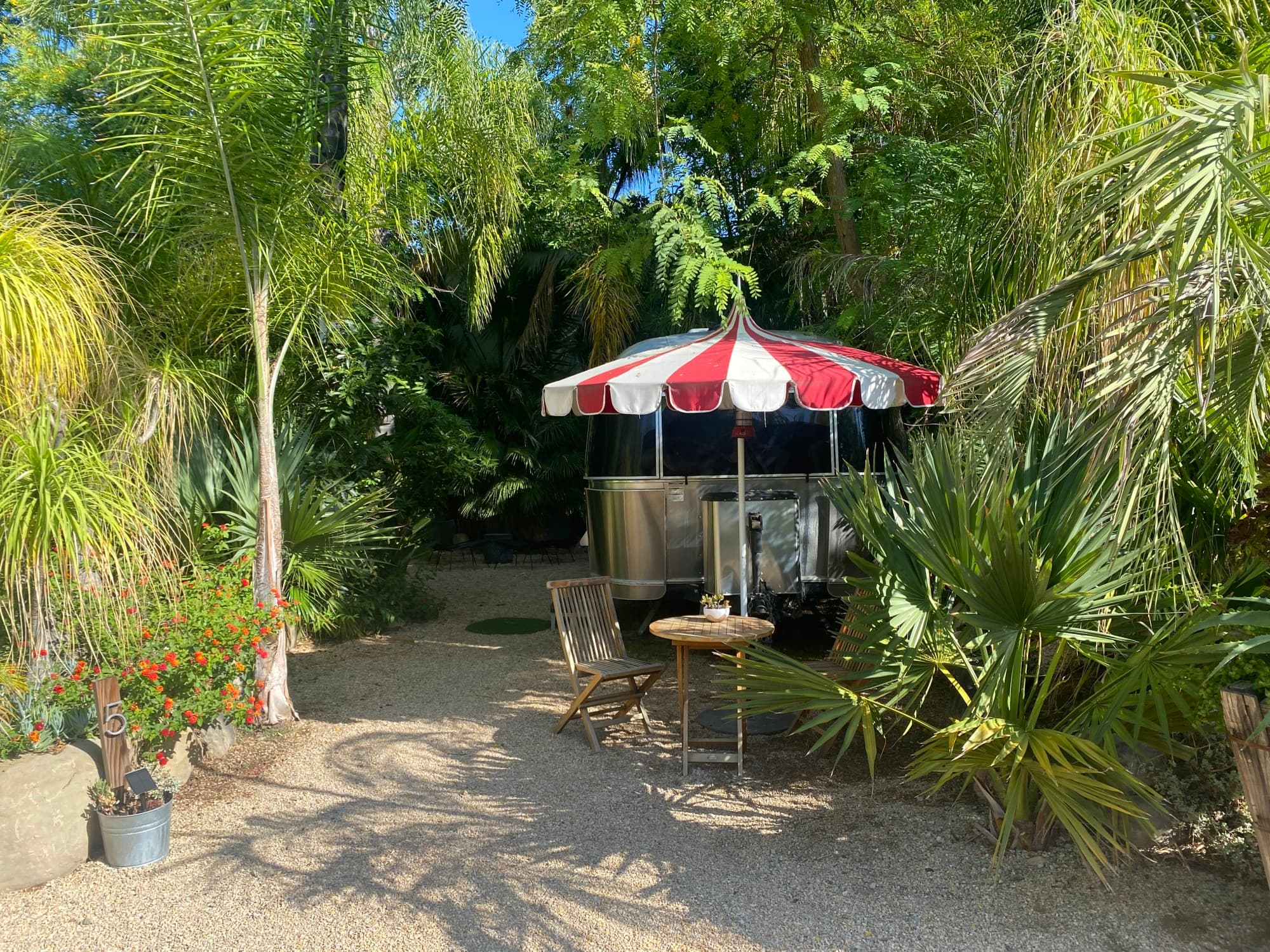 A food truck with an umbrella and chair outdoors.