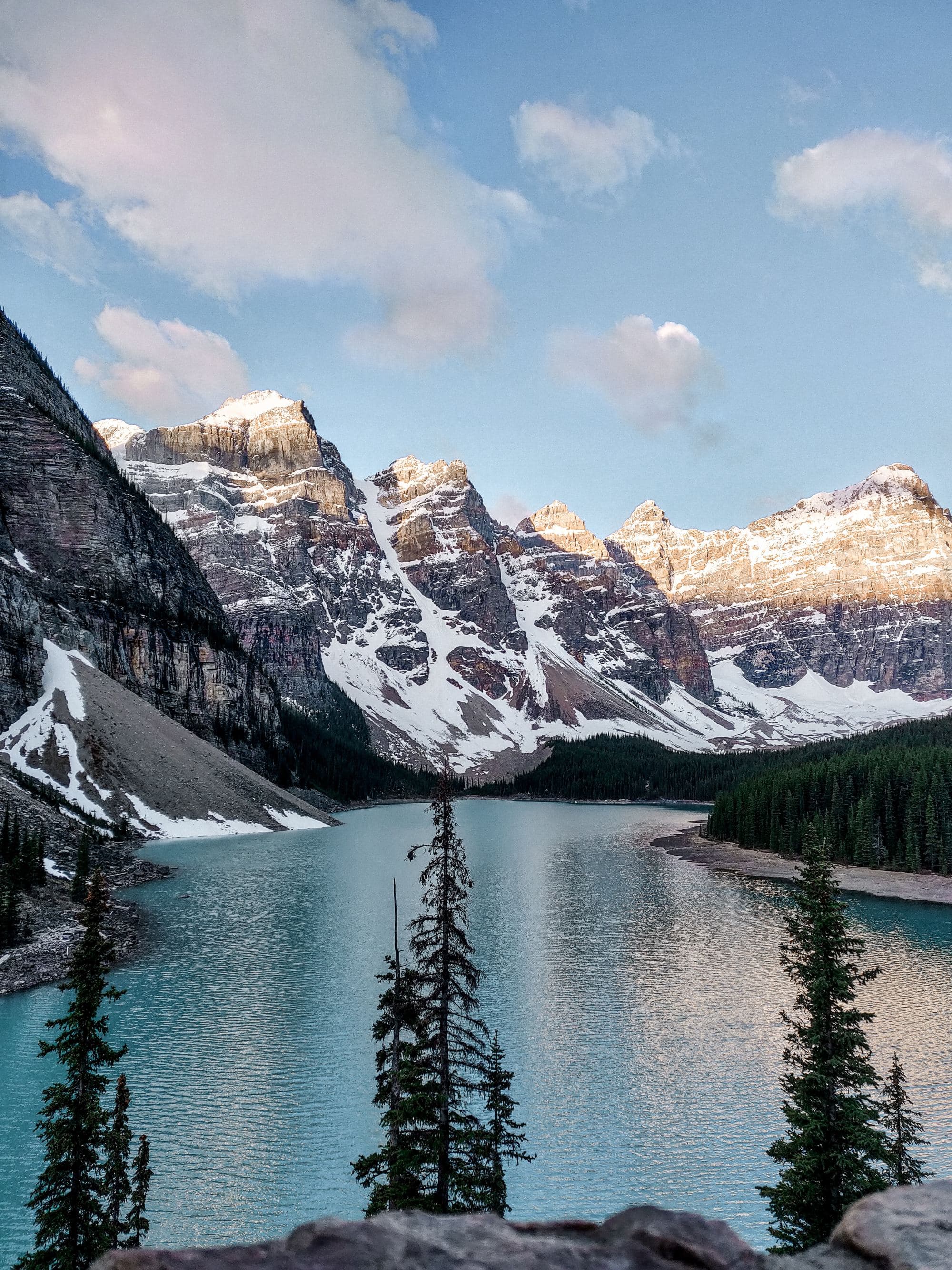 Lake near snow covered mountains under blue sky during daytime.