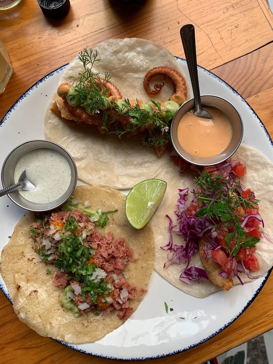 A plate with 3 tacos and two sauces.