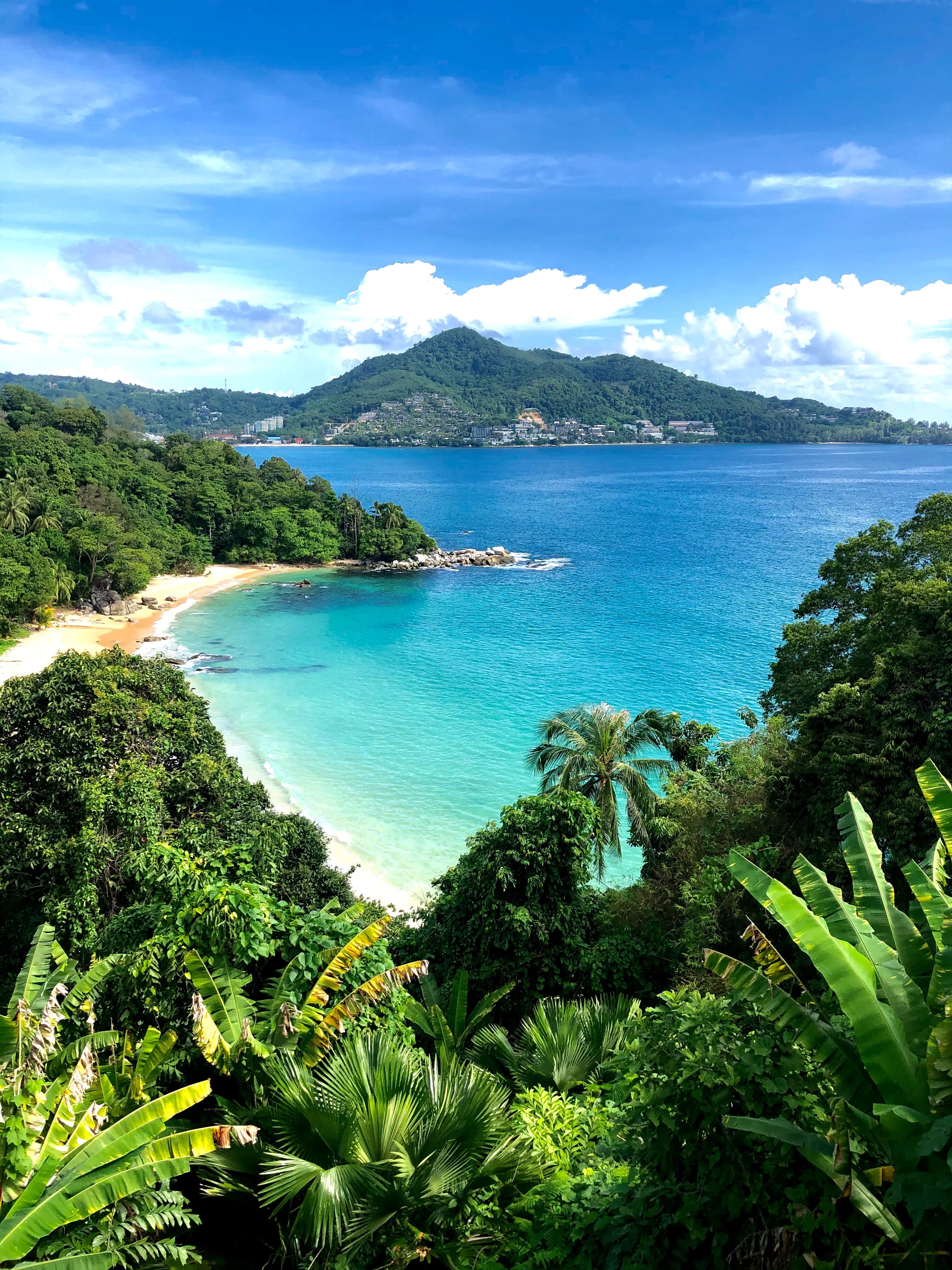 beach next to blue water with mountain in background during daytime