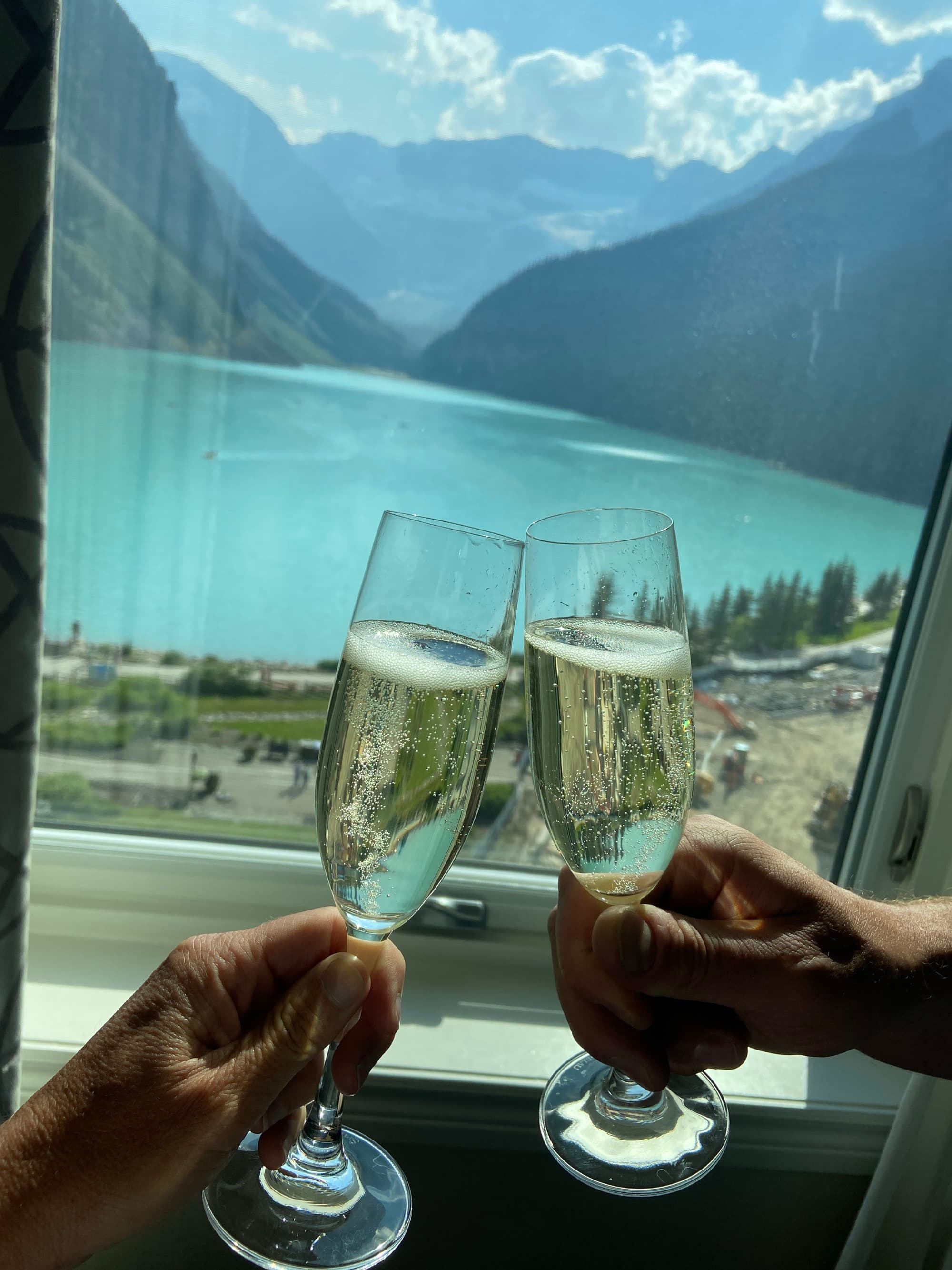 Two wine glasses being tossed in front of a lake.