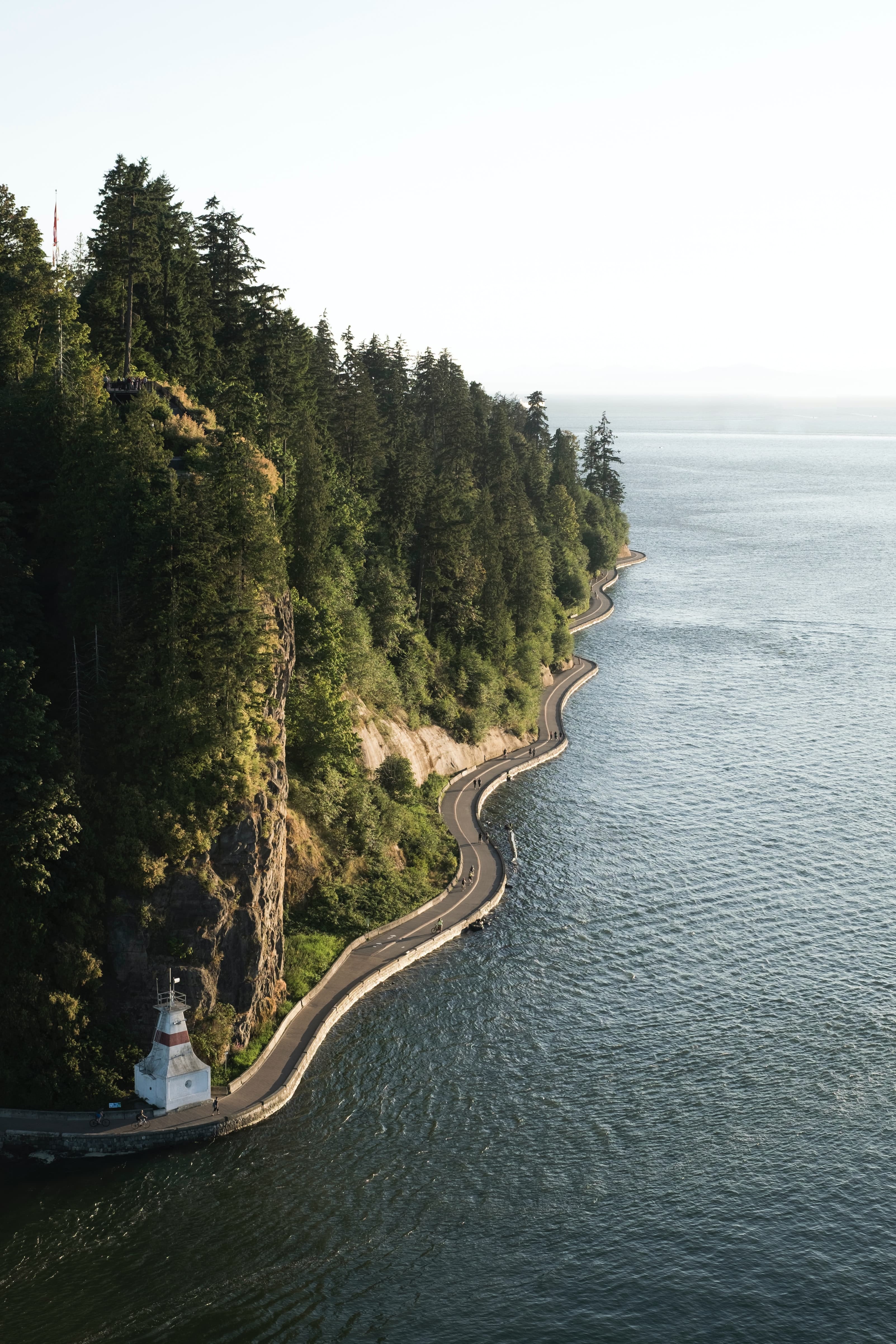 Aerial view of road next to water and trees on cloudy day