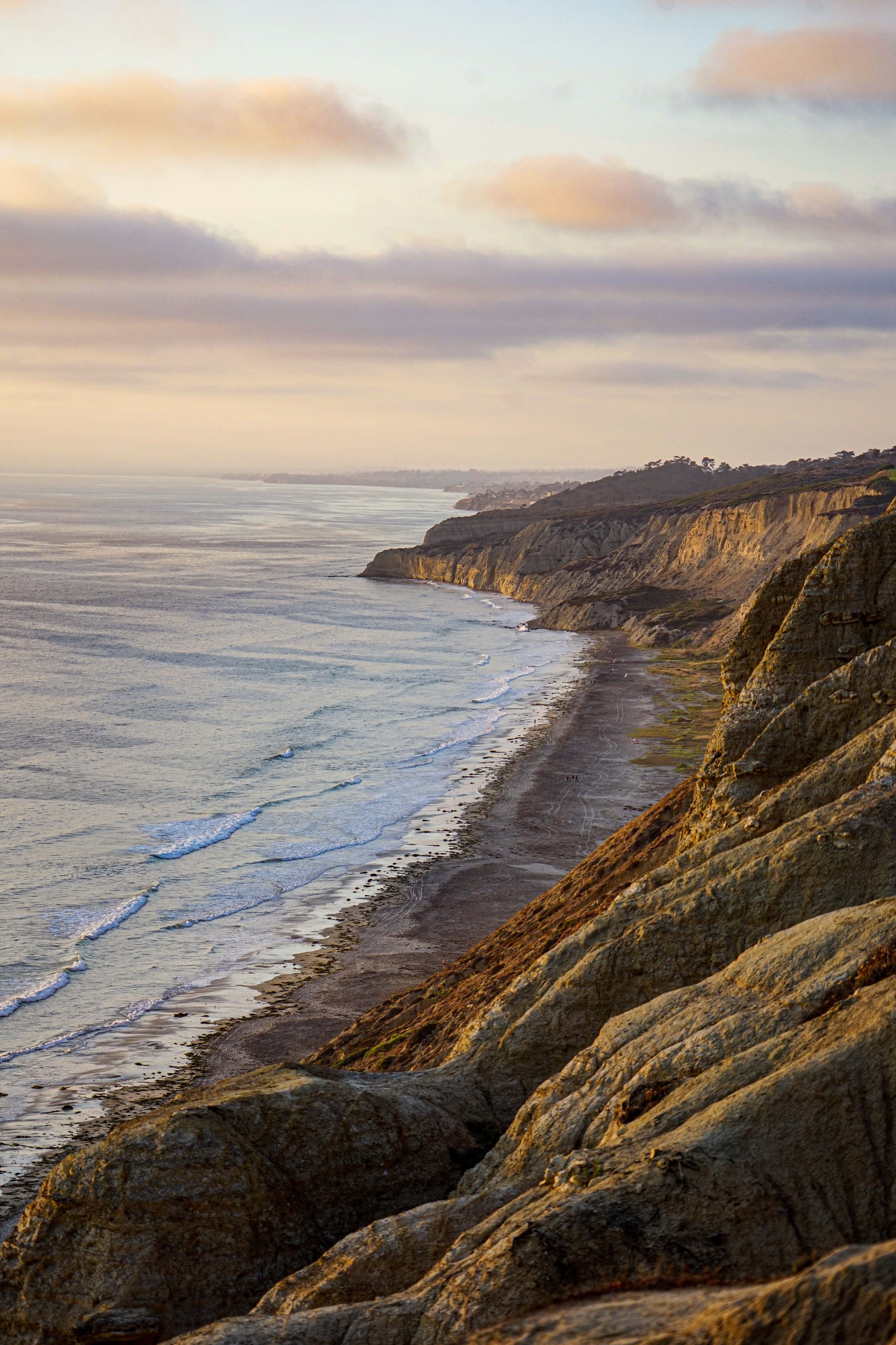 Ocean along coastline with pink and purple clouds