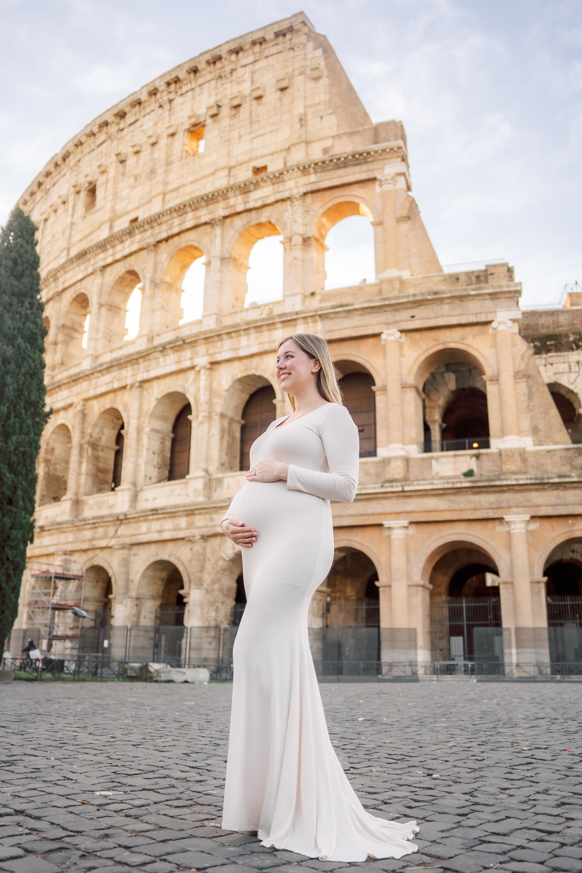 The image depicts an individual standing in front of the Colosseum in Rome during the daytime.