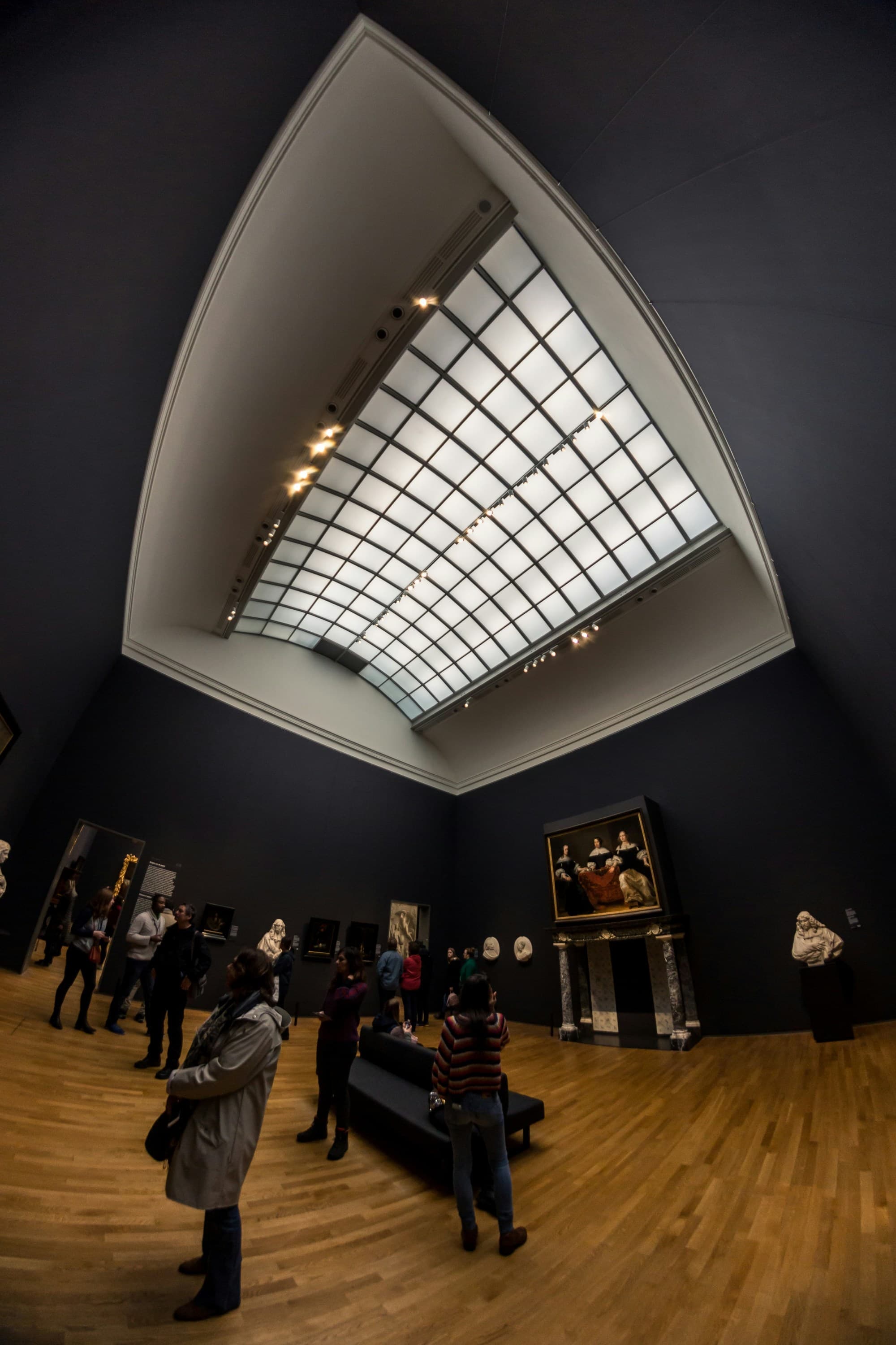 Rijks Museum features a modern skylight filtering light into the high-ceilinged gallery space as guests peruse art.