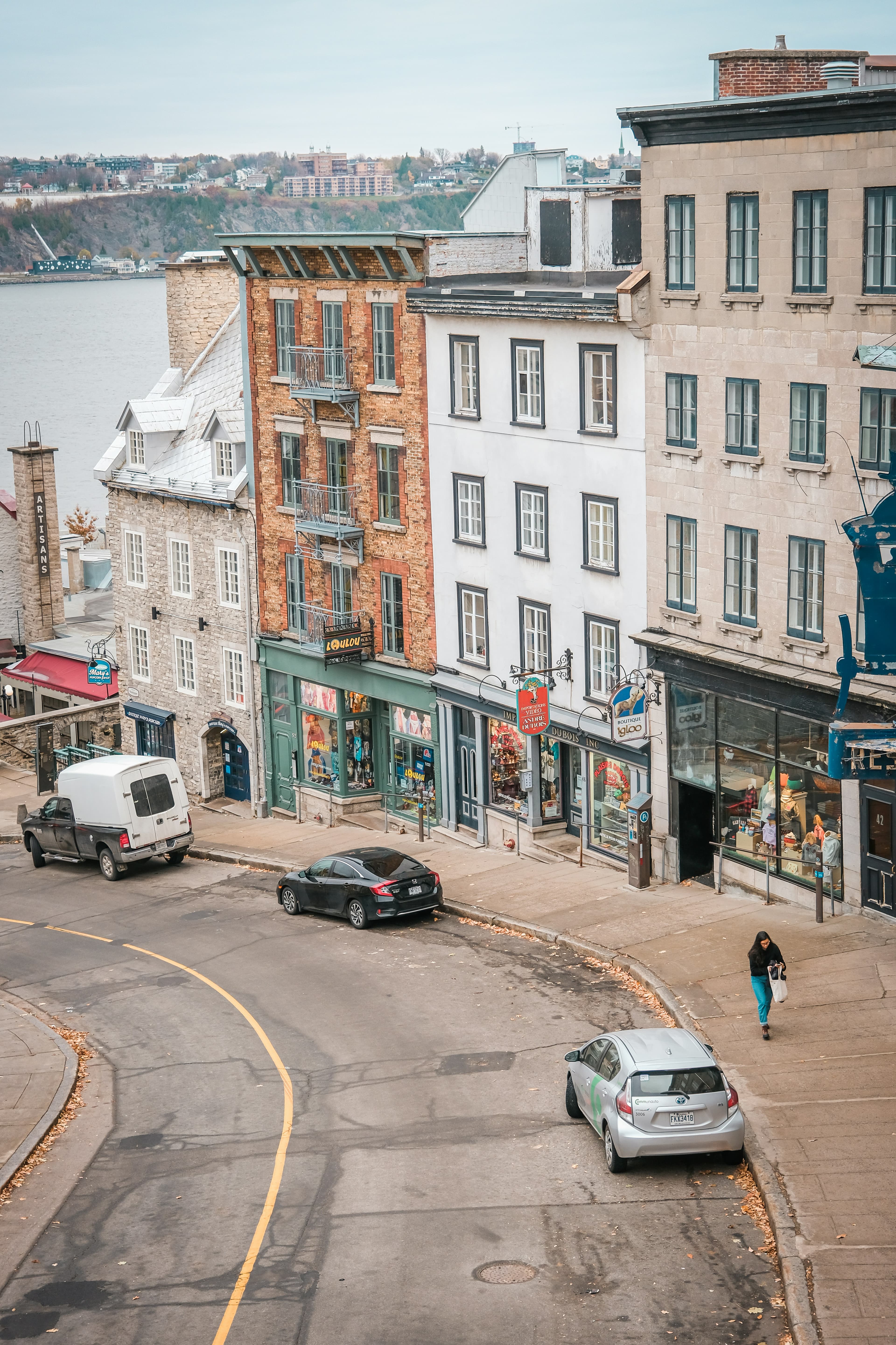 A view of a downward sloped street in Old Quebec with quaint buildings and stores.