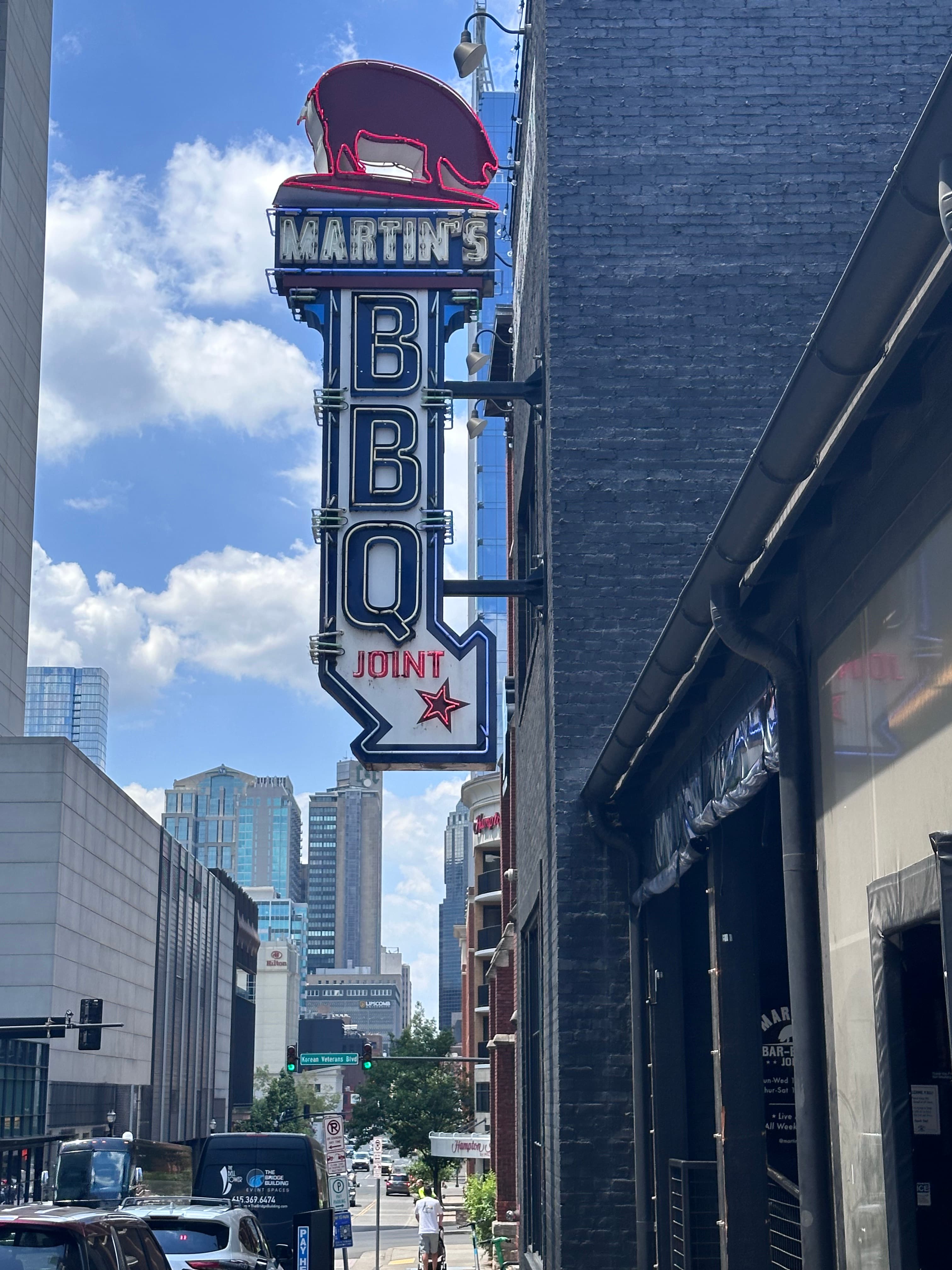 Signboard of BBQ joint on a side street on a cloudy day.