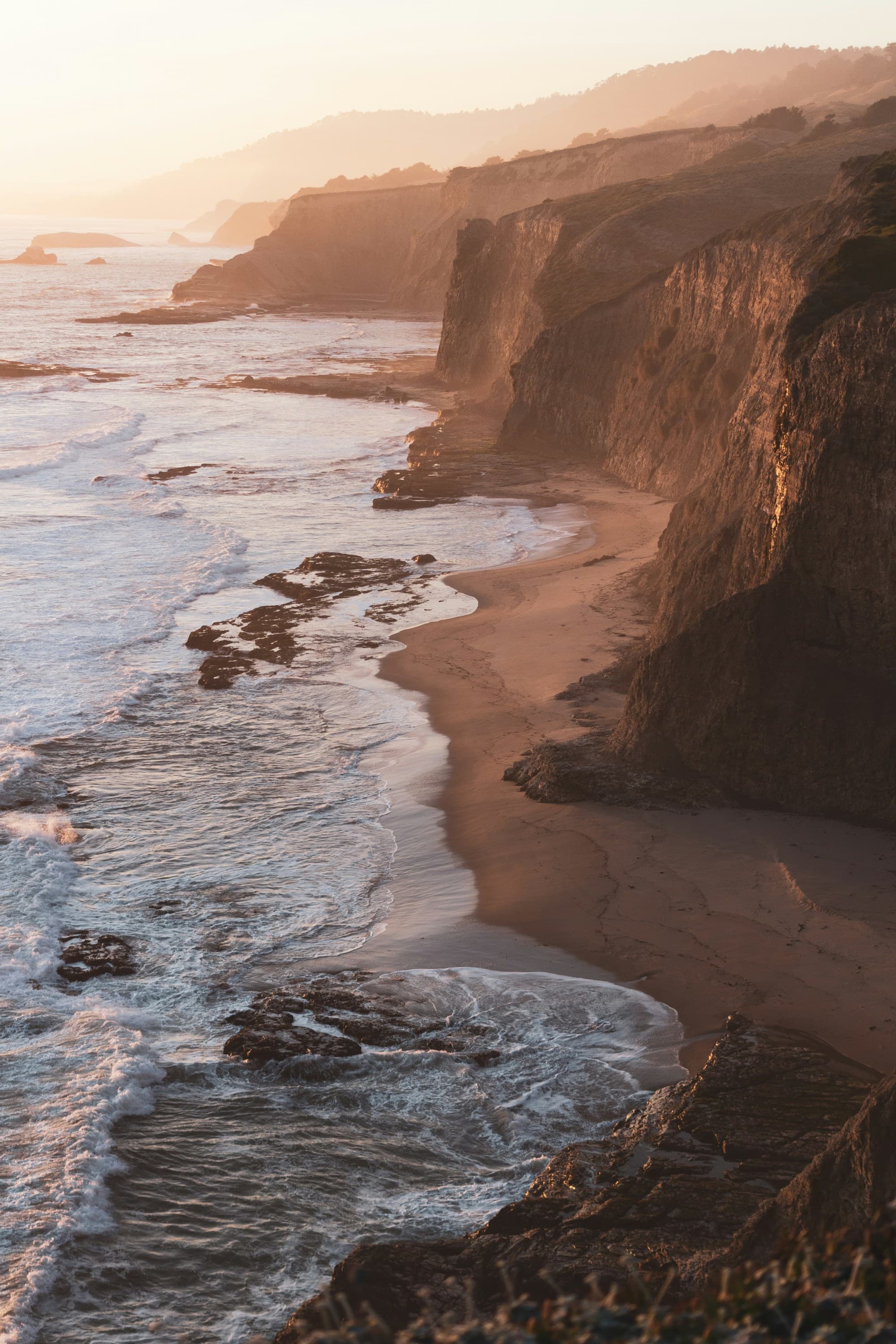 A cliffy coastline on the beach during sunset