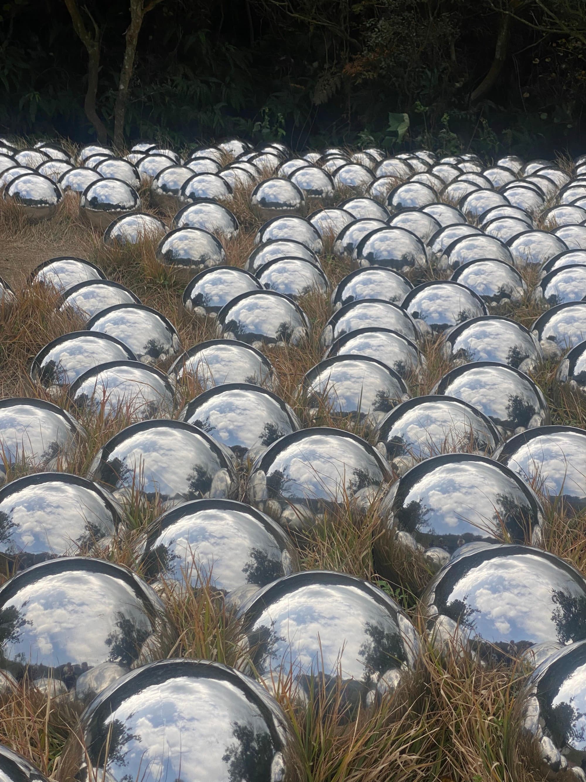 A picture of multiple glass sphere in a field during daytime.