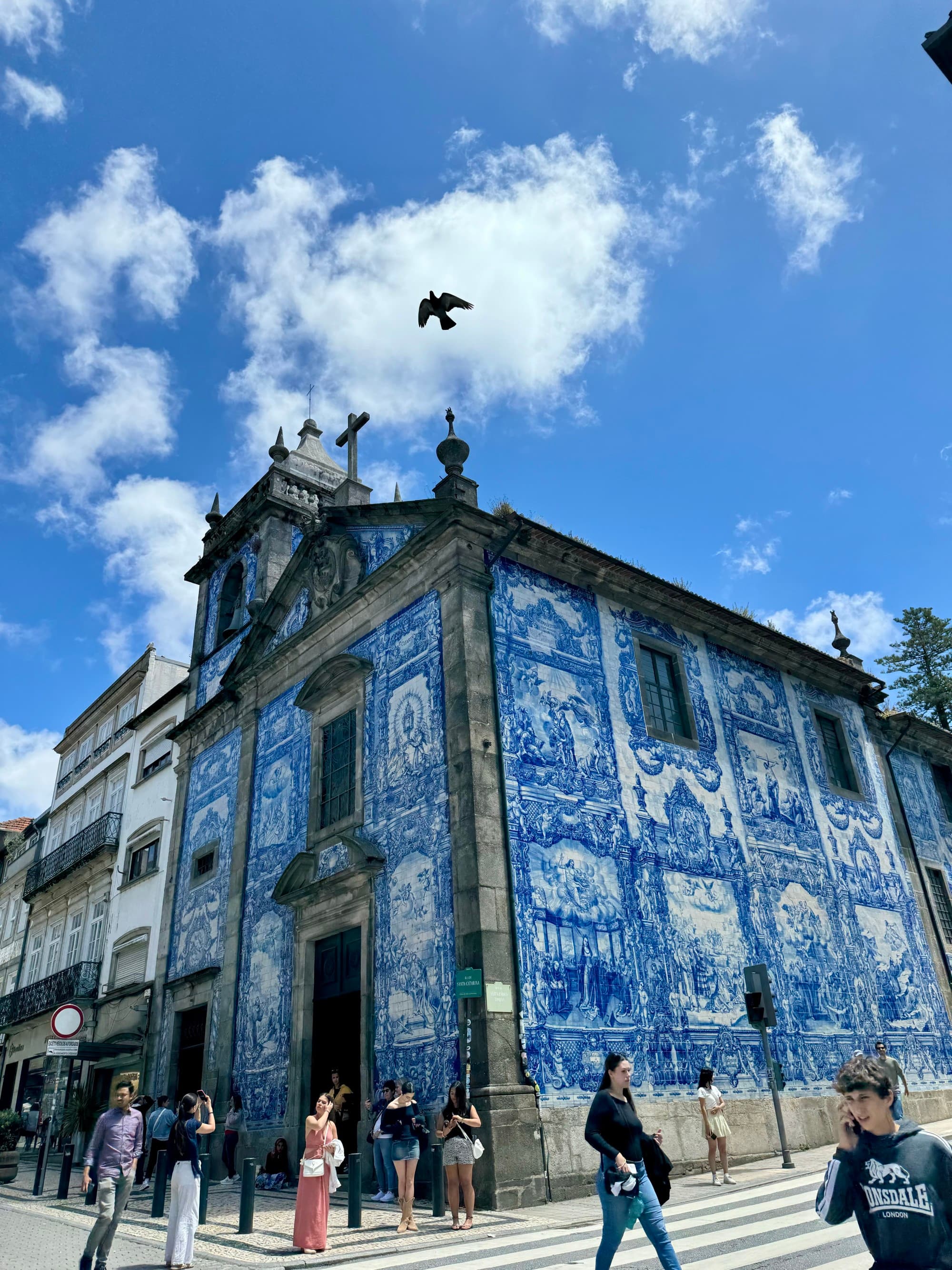 A blue and white tile church on a street corner on a sunny day.