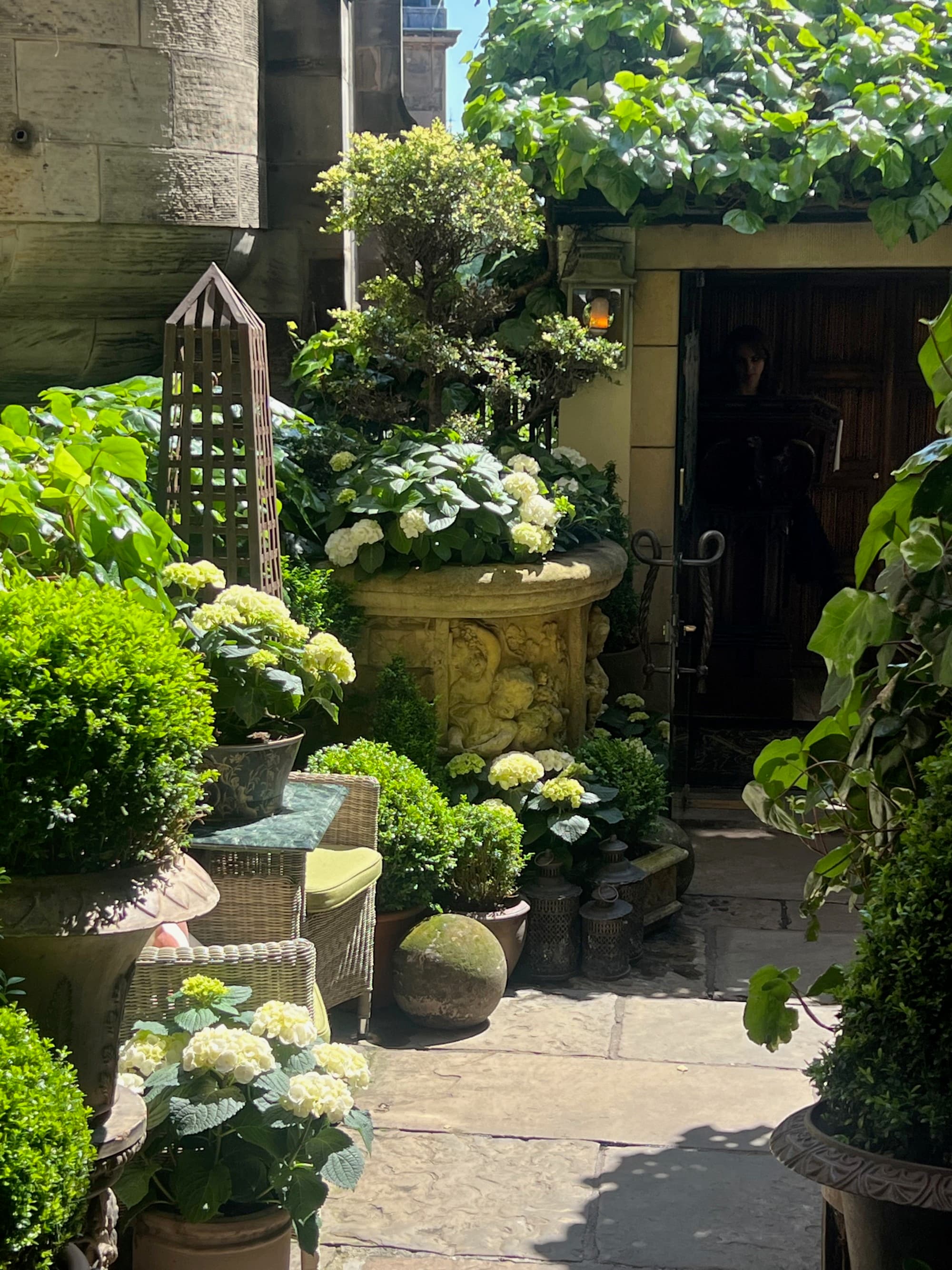 A sunny garden alcove with hydrangeas and a stone fountain, at a place to get afternoon tea Edinburgh.