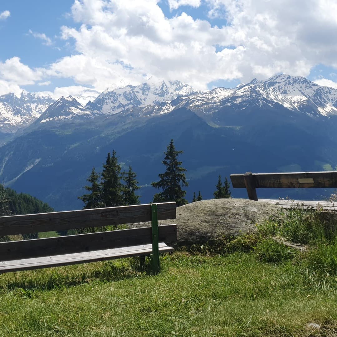 Bench with view of snow covered mountain peaks.