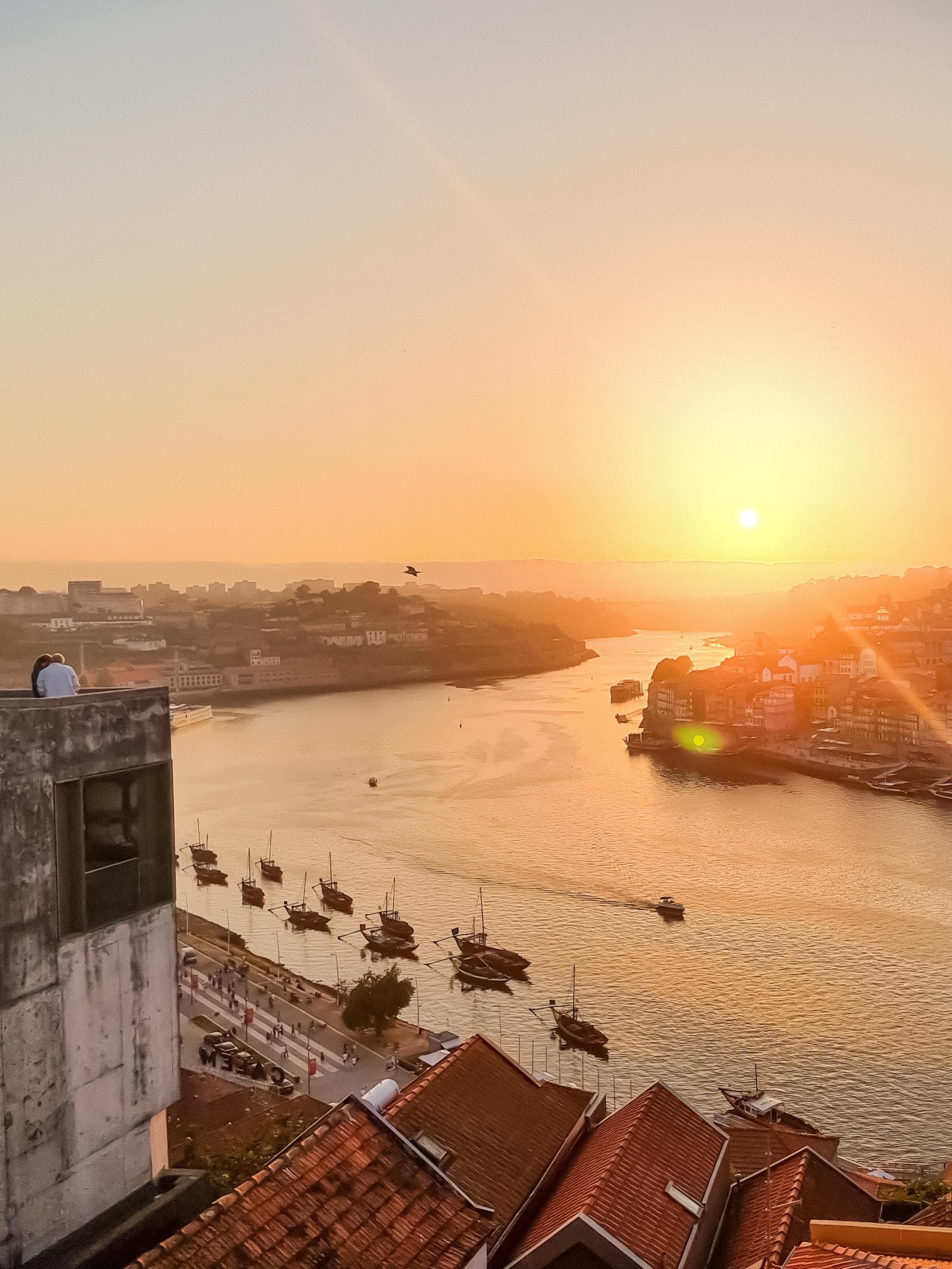 view atop an old coastal city during a vidid orange sunset with boats on the calm ocean