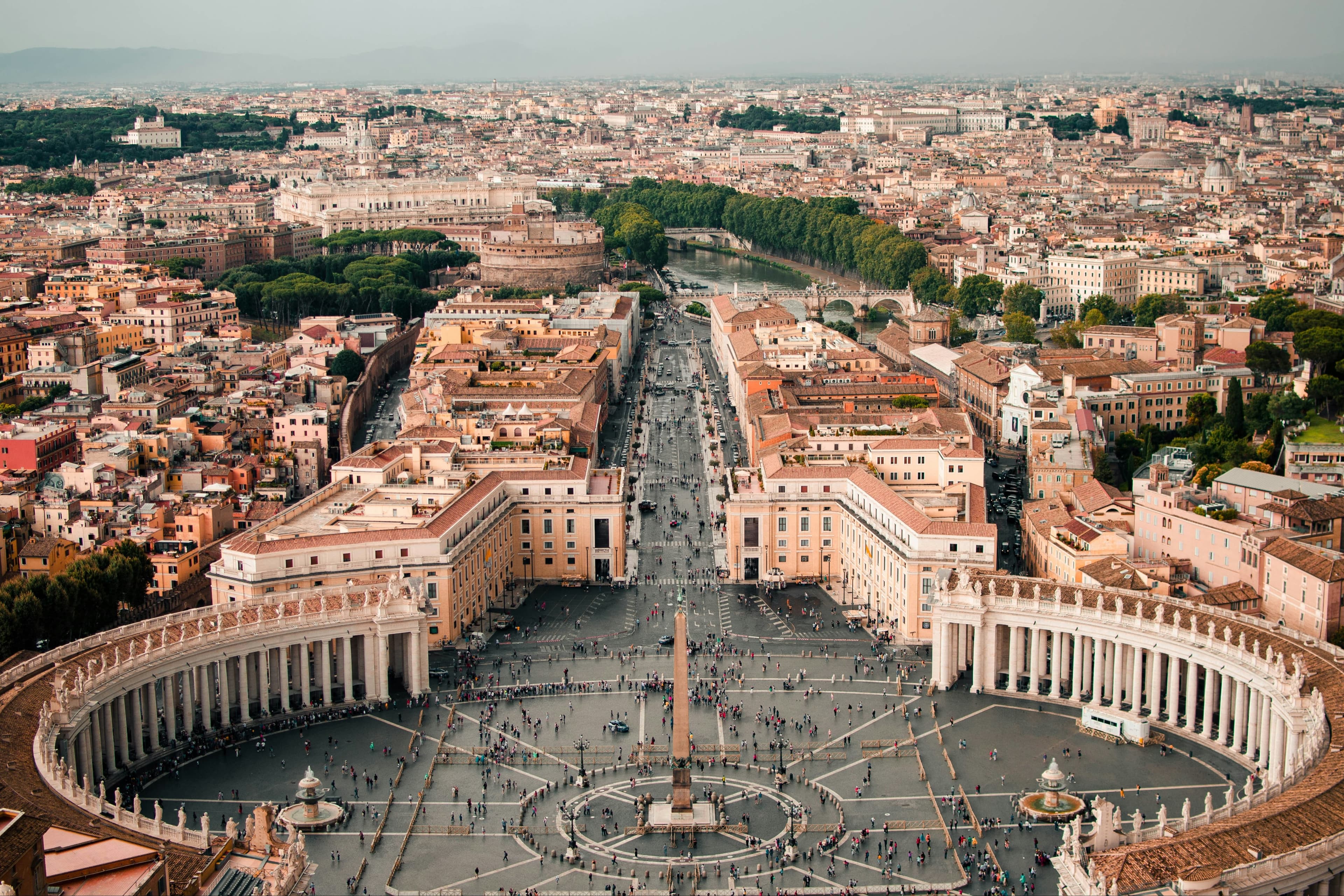 An aerial view of Northern Italy with tan buildings, green trees and a city center.