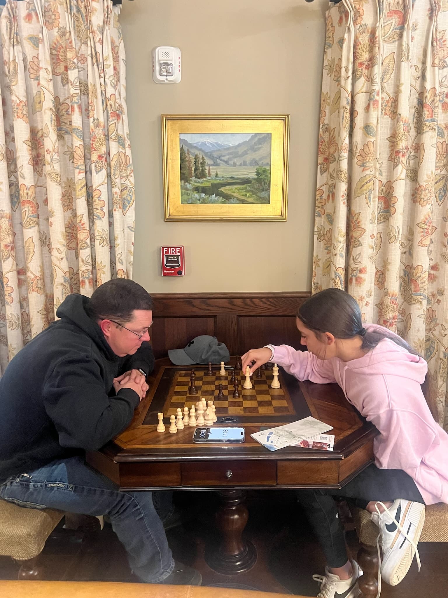 Two people sitting at an indoor table playing chess