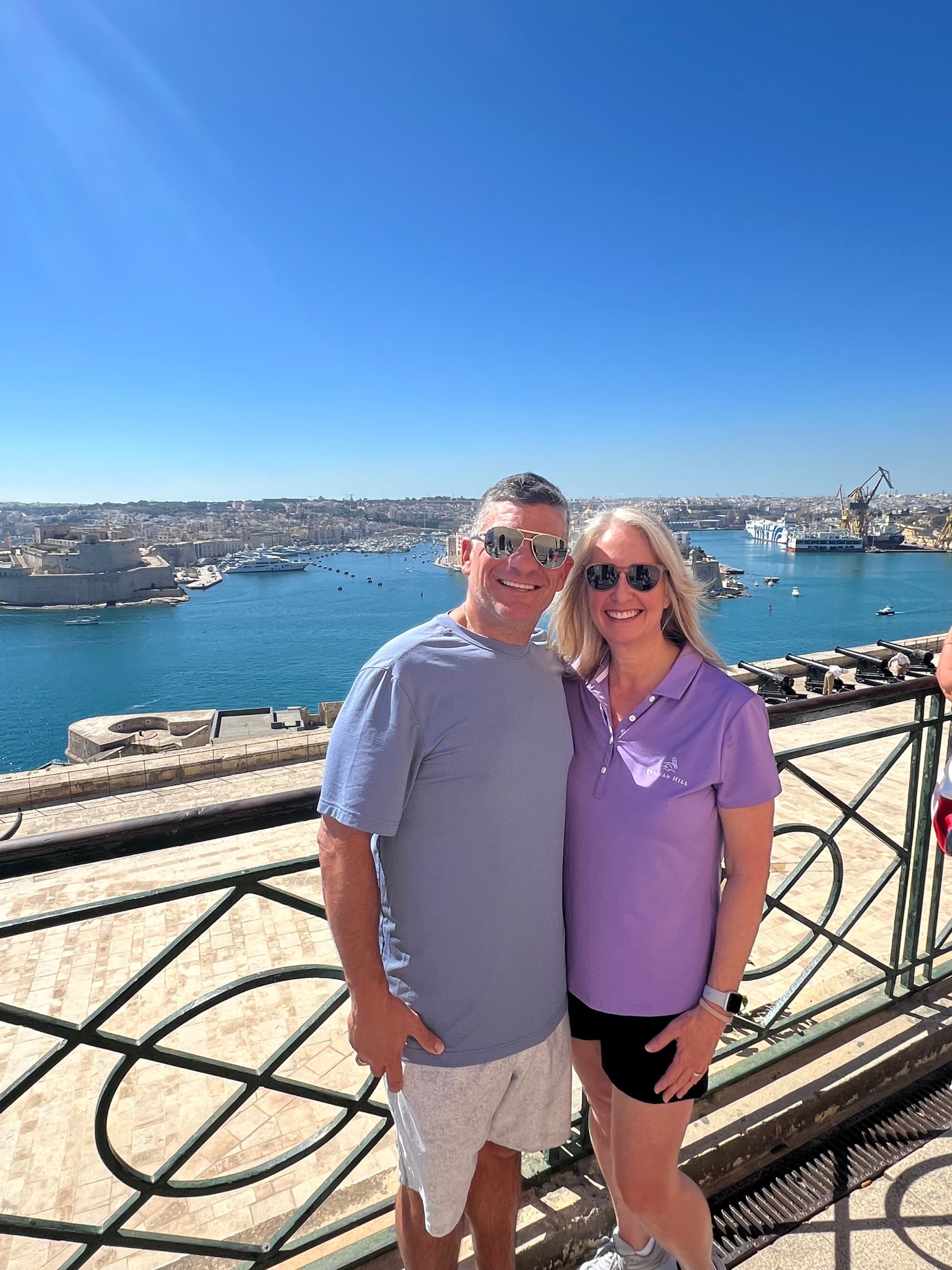 Couple posing on the seaside in front of a wrought iron railing.