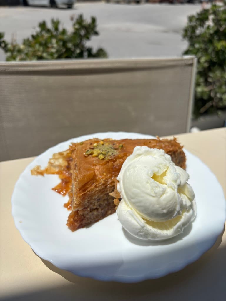 A slice of orange pie on a plate next to a dollop of vanilla ice cream.