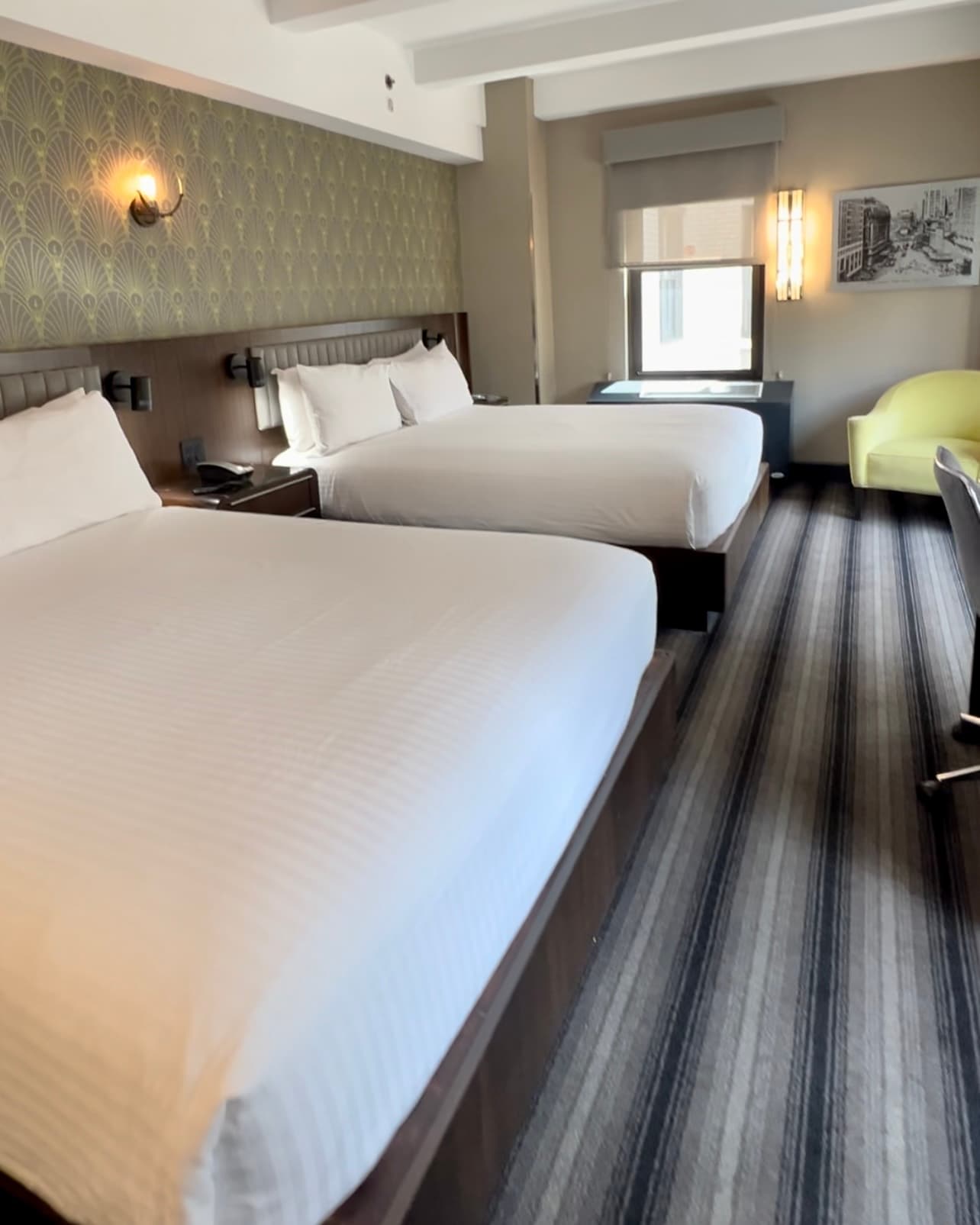 Two king-sized beds next to each other with crisply tucked white sheets.