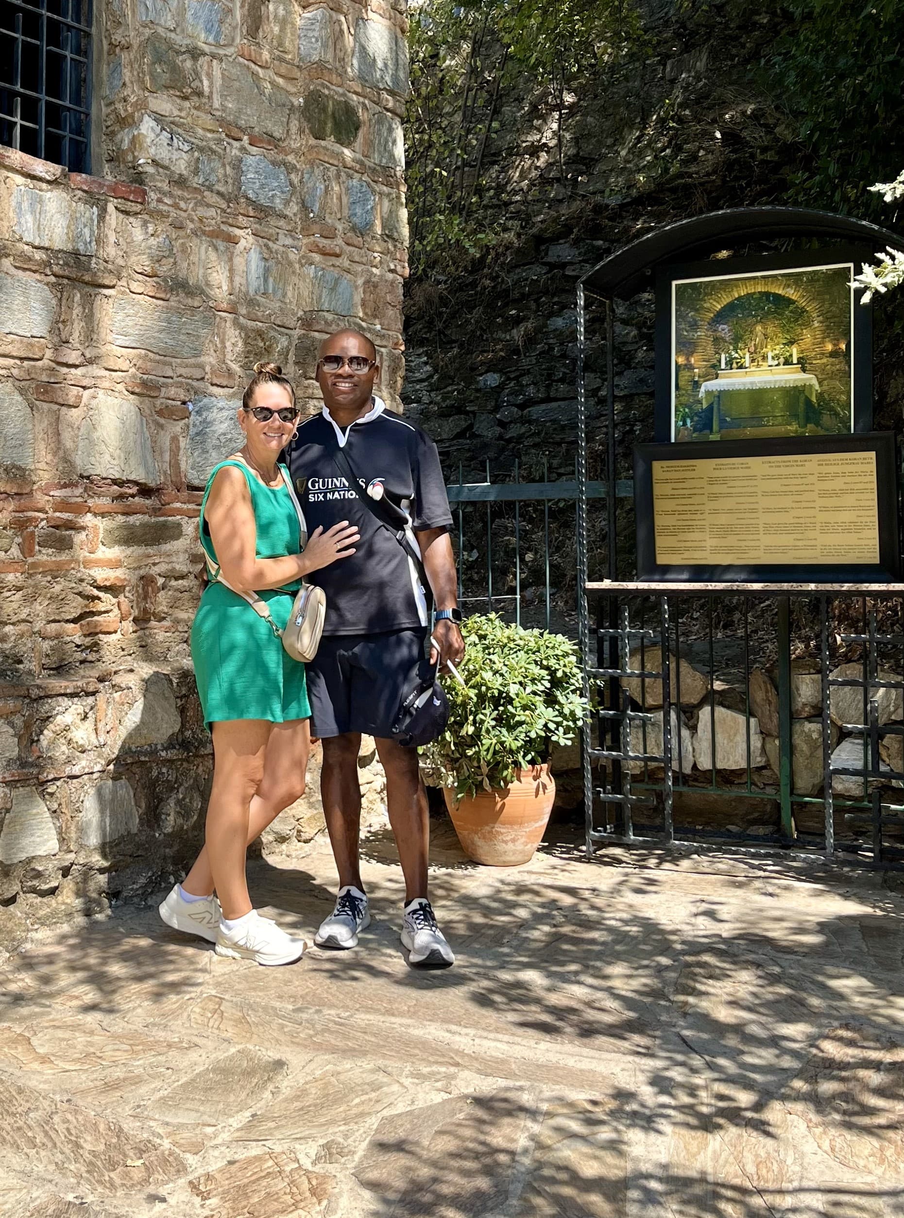 A couple standing outside a stone building next to signage.