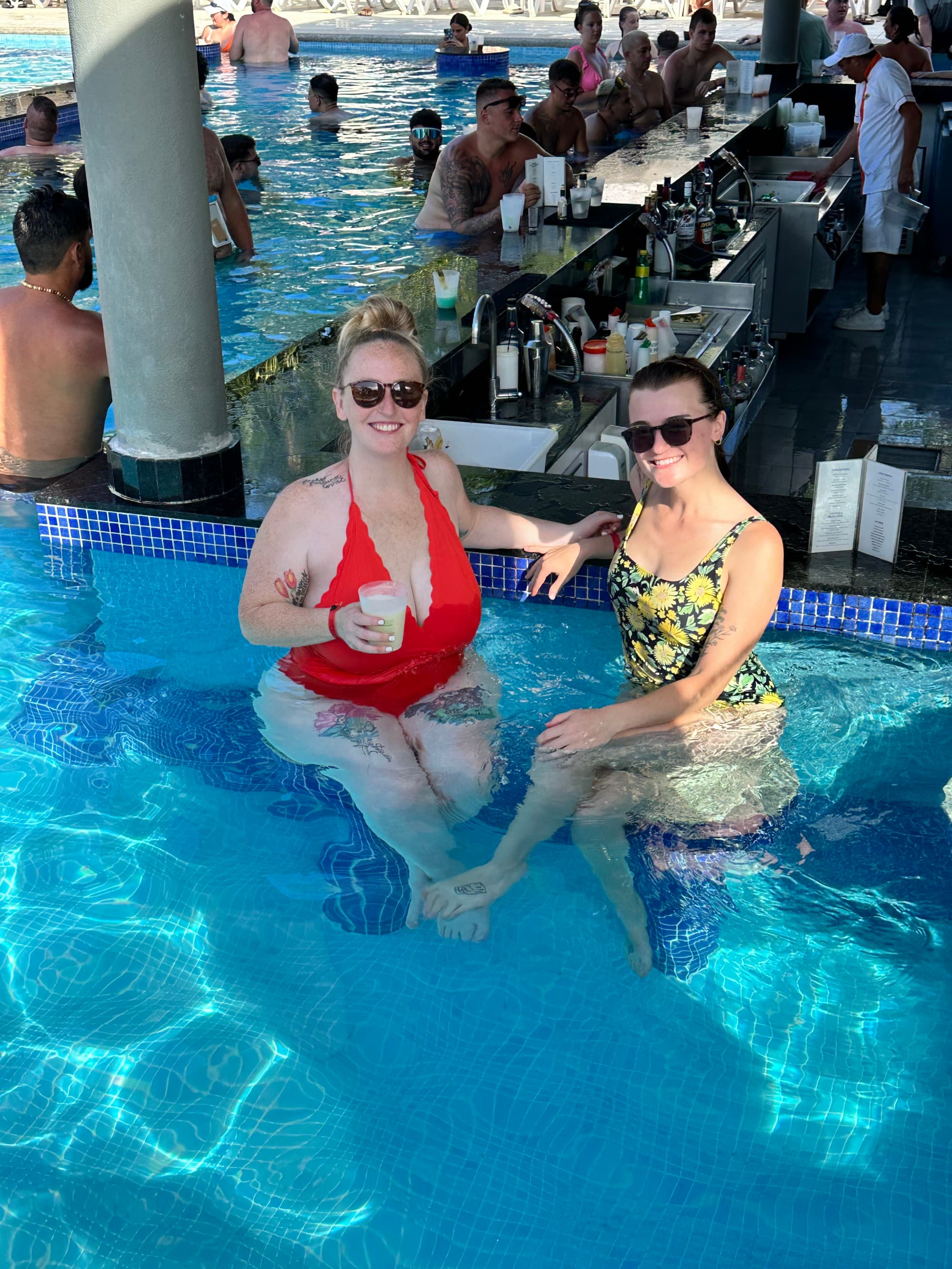 Two people sitting in a swimming pool posing for a photo