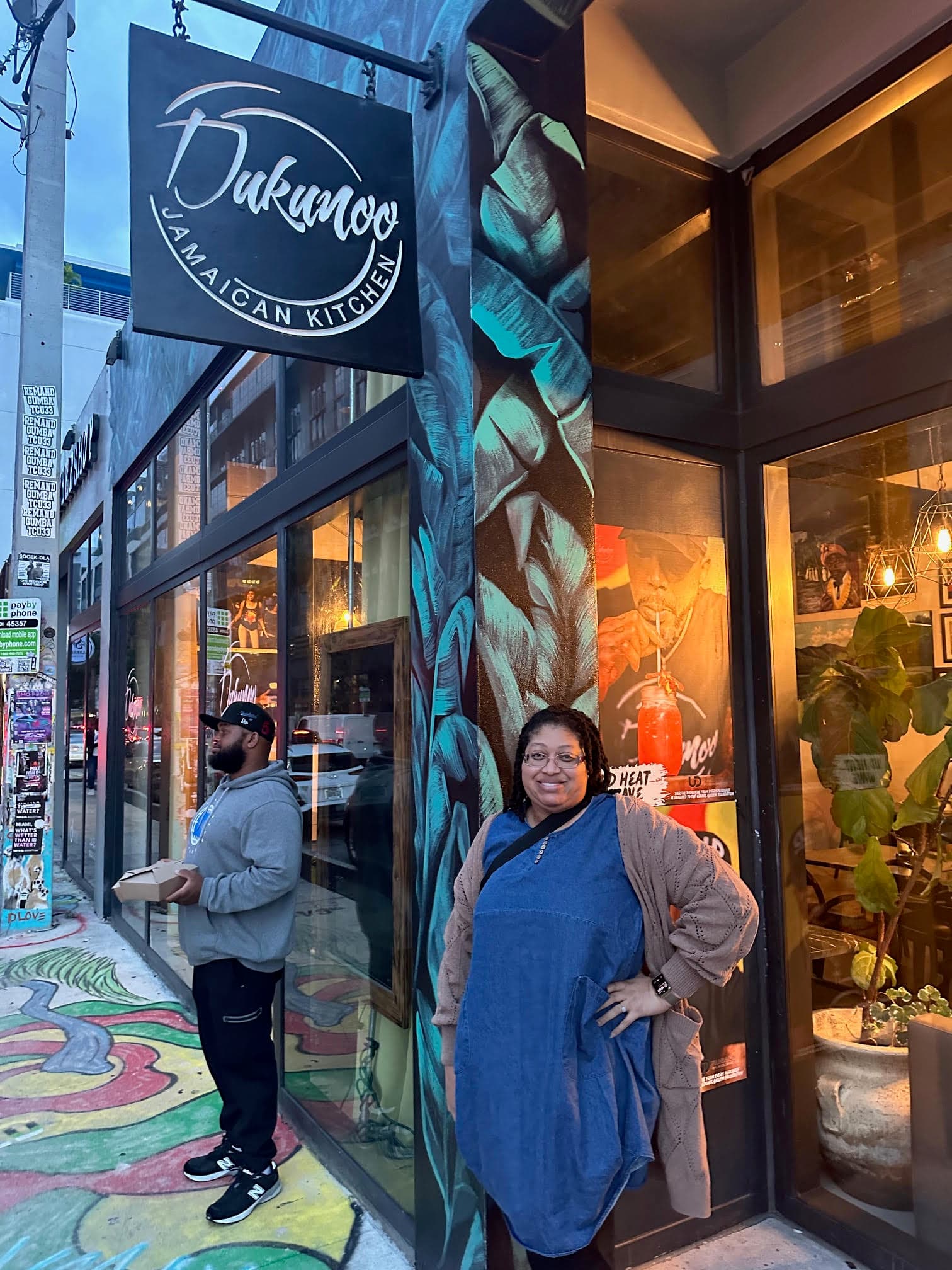 A person posing for a photograph under a restaurant sign