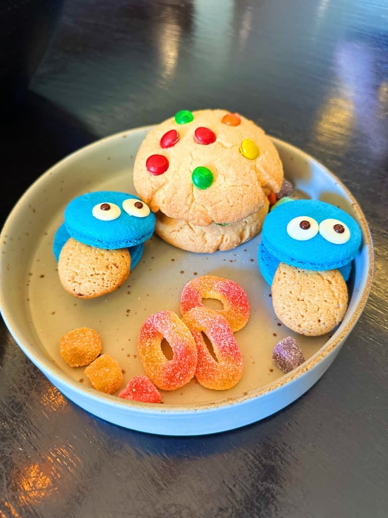 A plate of cookies and gummy worms.