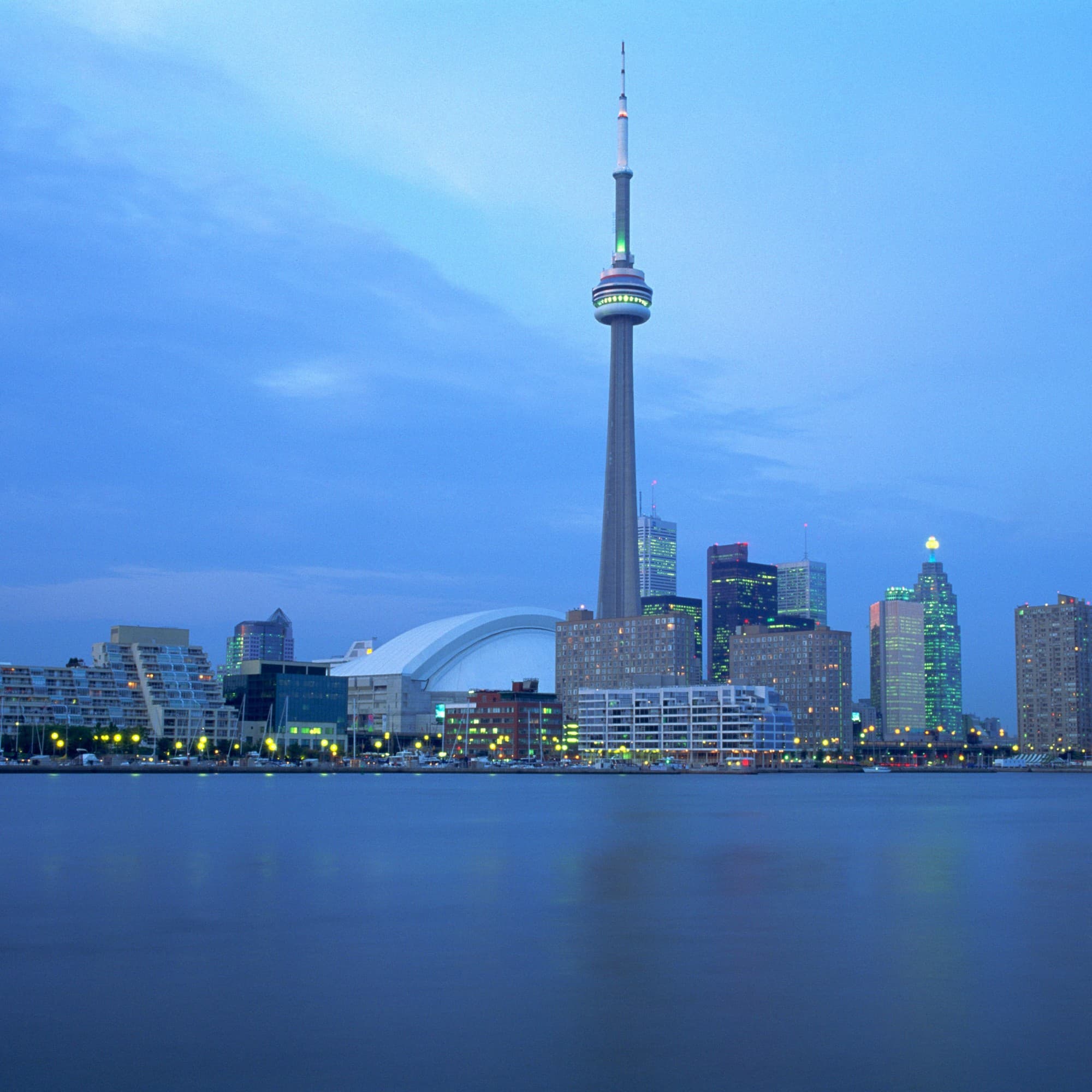 Toronto’s skyline on the water with the CN Tower against the evening glow.