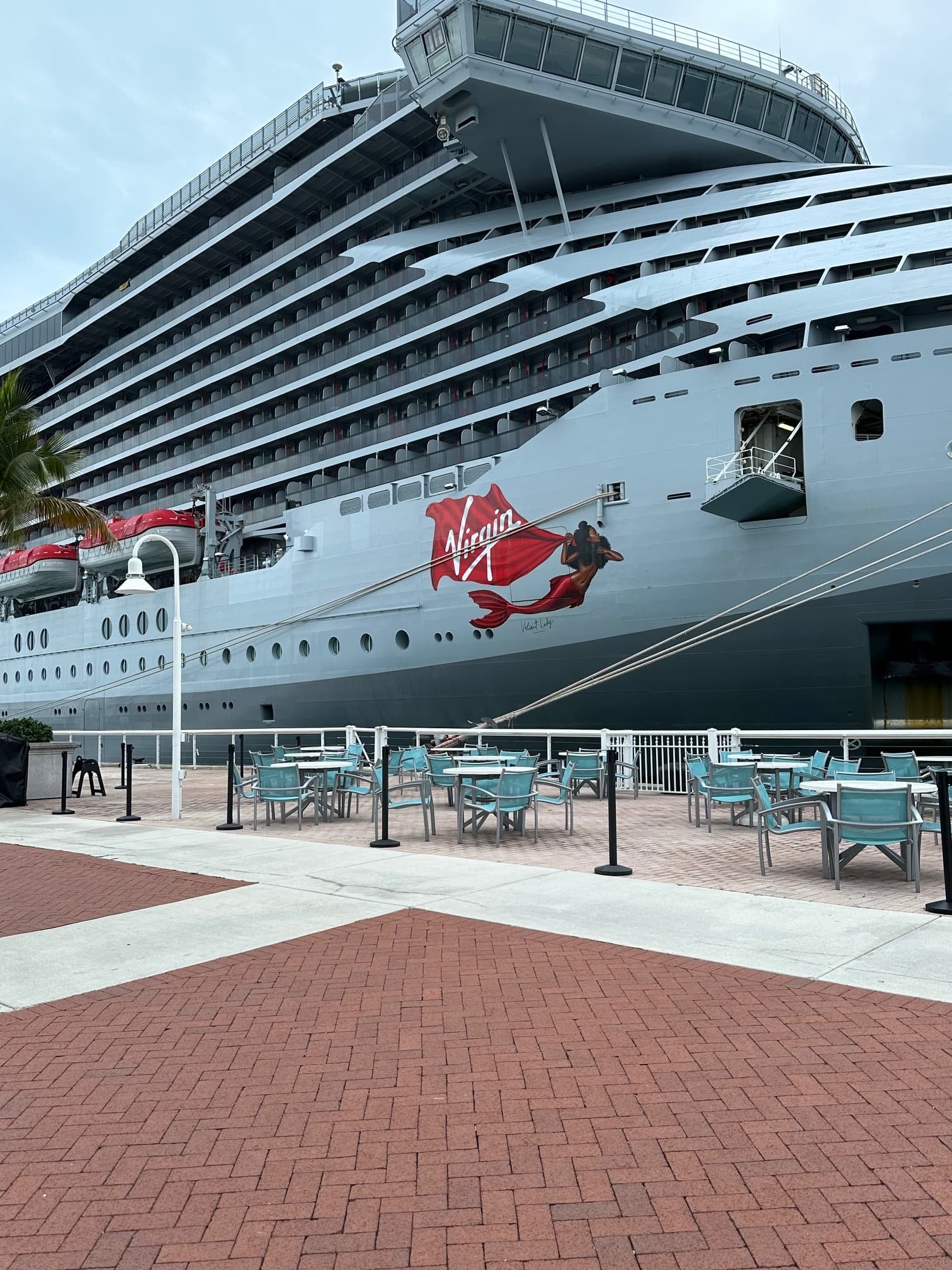 Virgin Voyages' ship Valiant Lady docked at a Port on a sunny day.