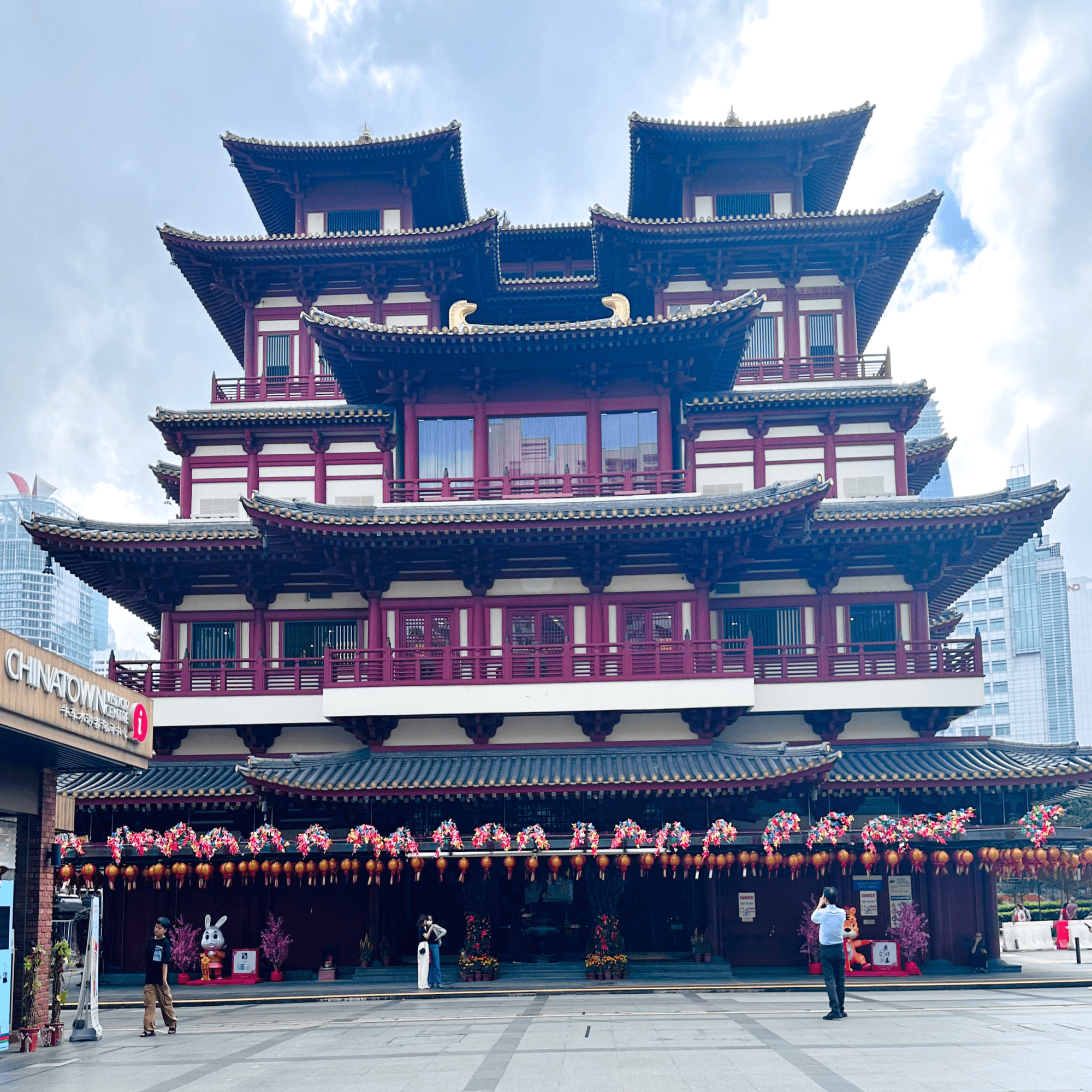 A traditional Chinese building with intricate red and gold decorations against a modern cityscape.