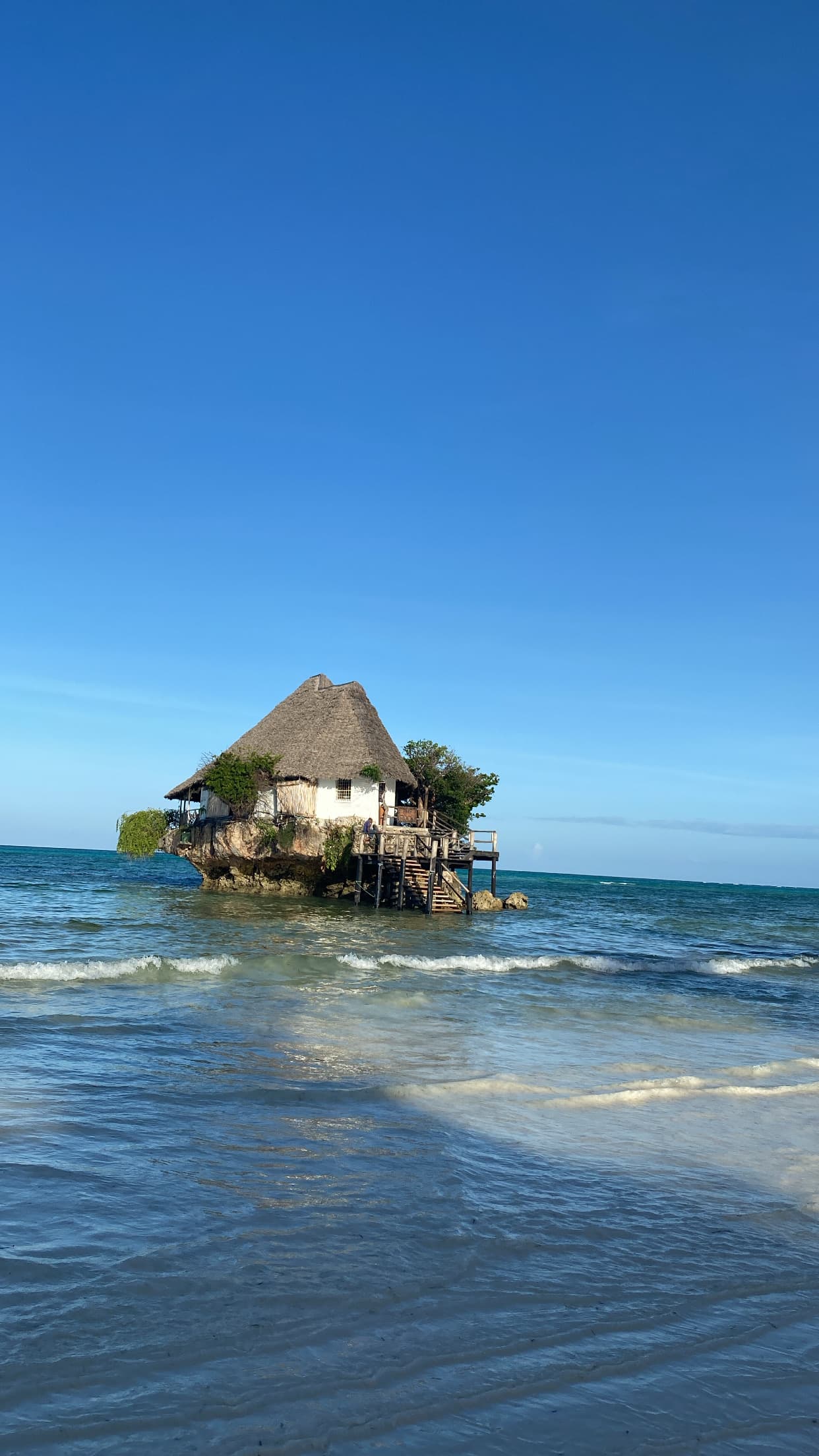 A hut over water in the ocean on a sunny day.