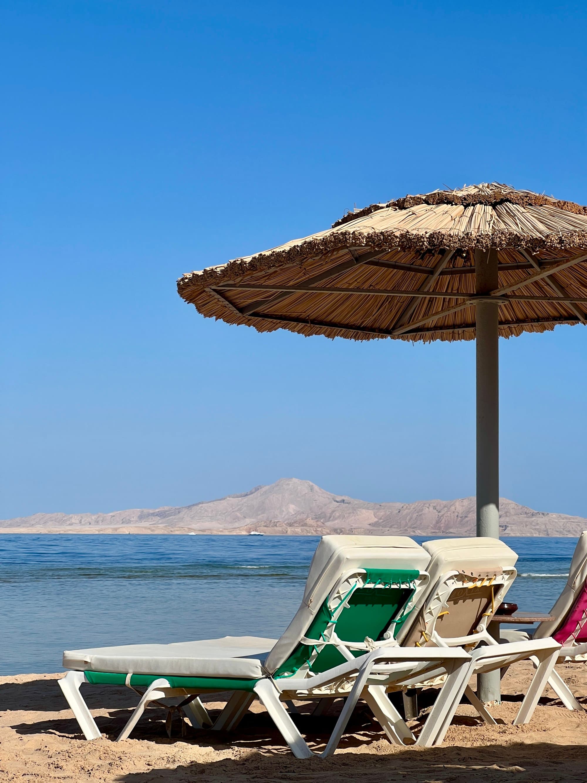 Beach chairs and straw umbrella on a beach.