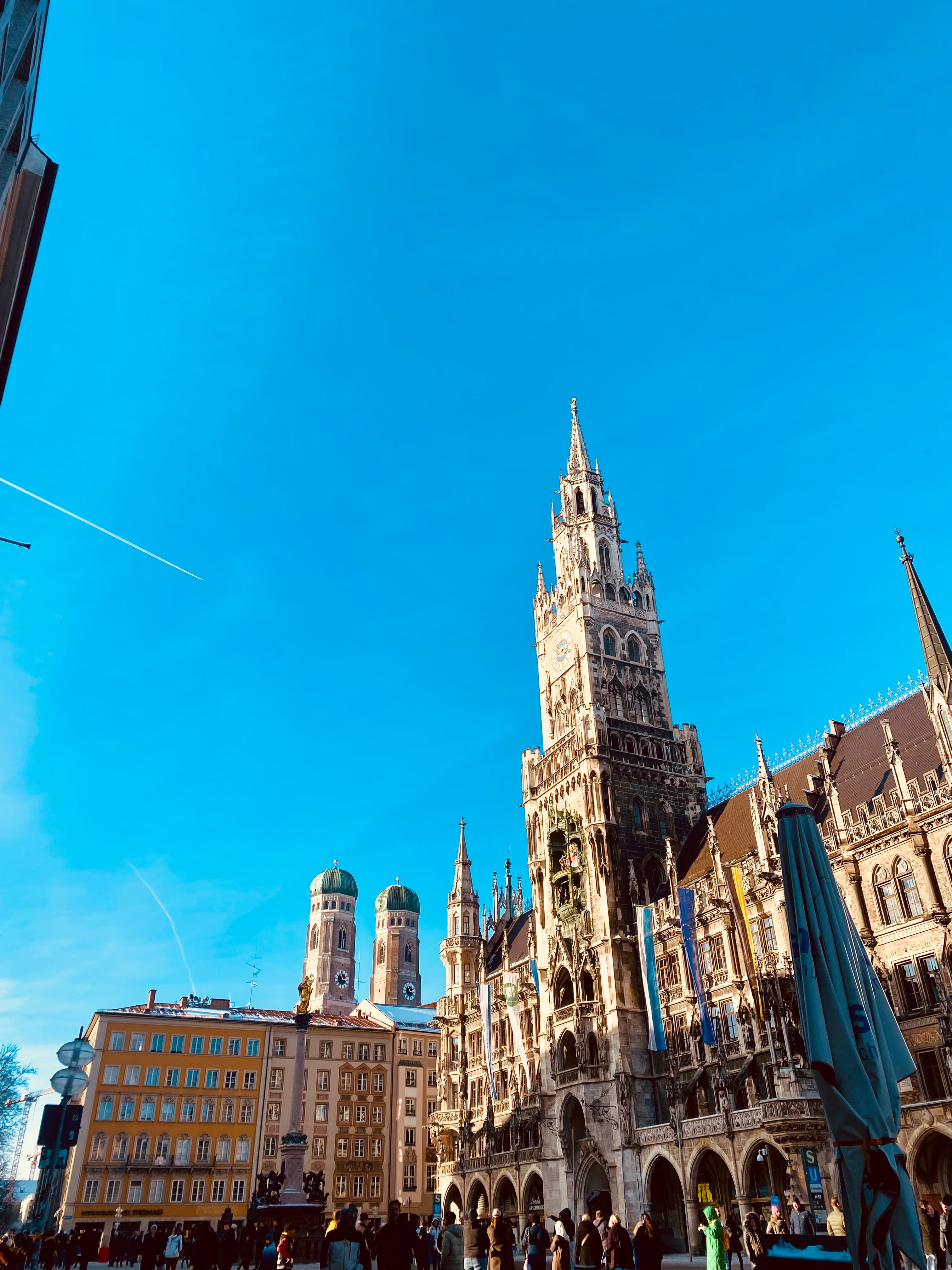 Marienplatz, Munich's vibrant central square, with ornate buildings and a bright blue sky.