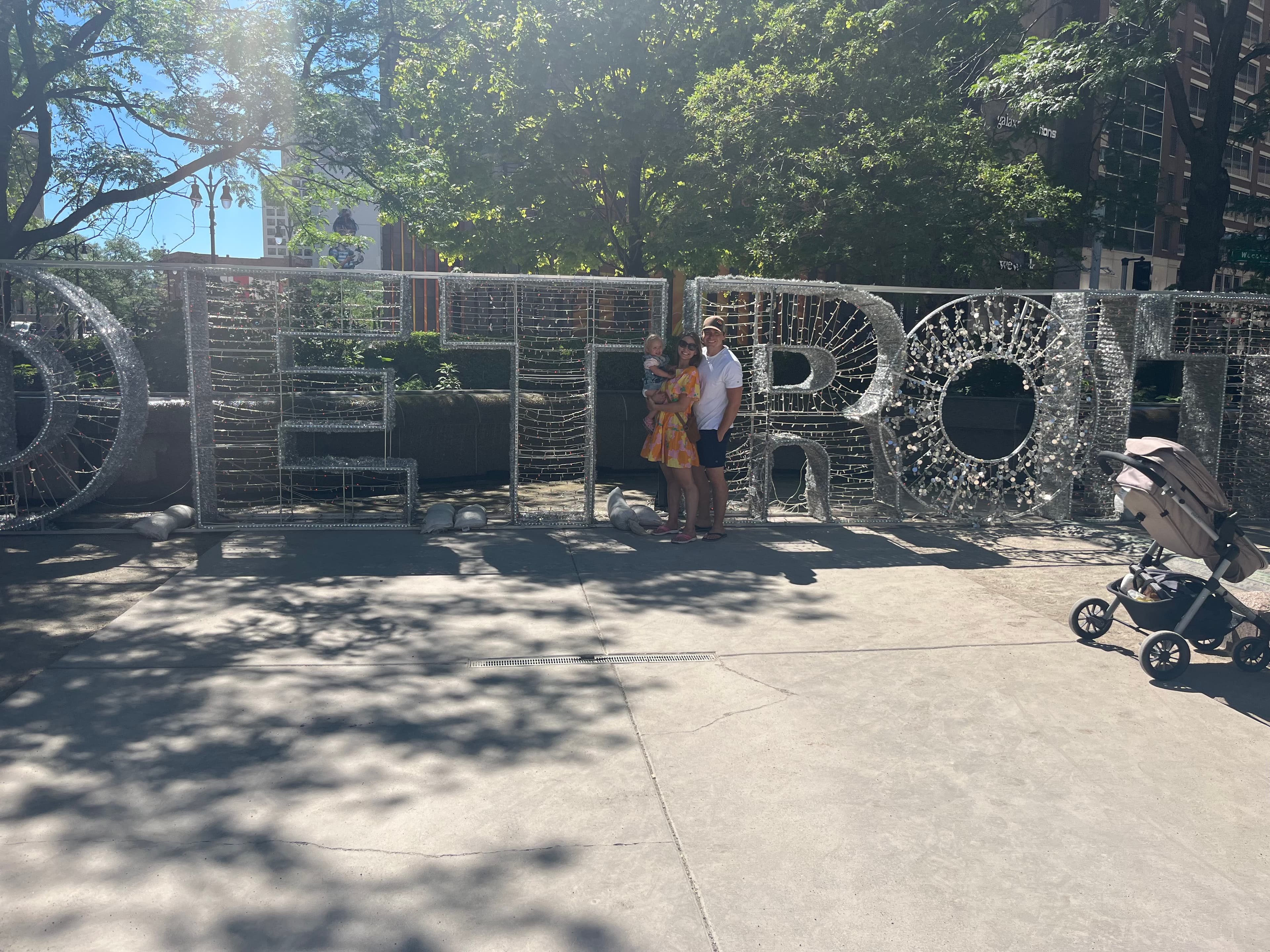 A picture of a man, woman and child standing in front of letters making up the word DETROIT