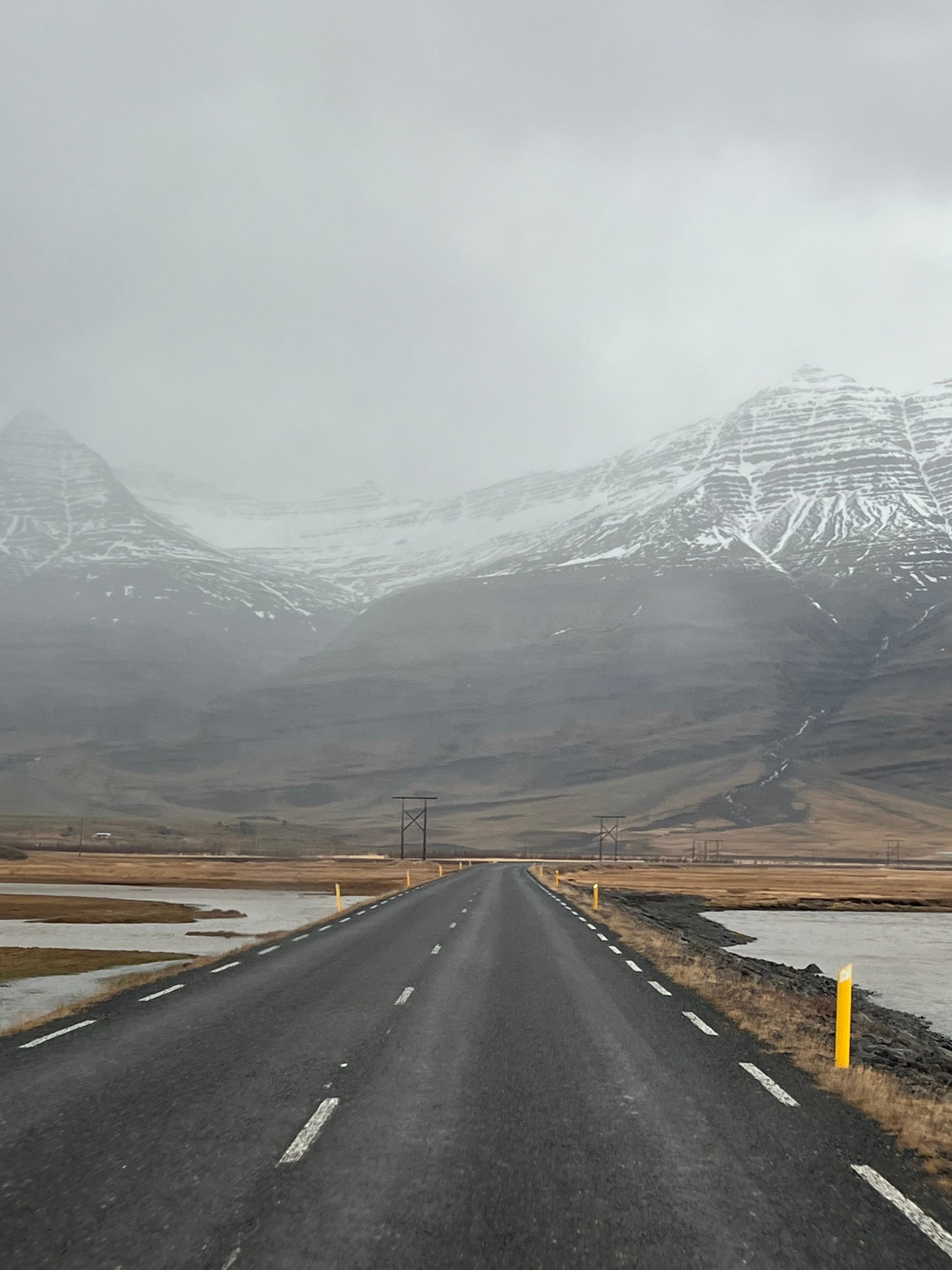 A serene mountainous landscape enveloped in mist, as seen from an empty road