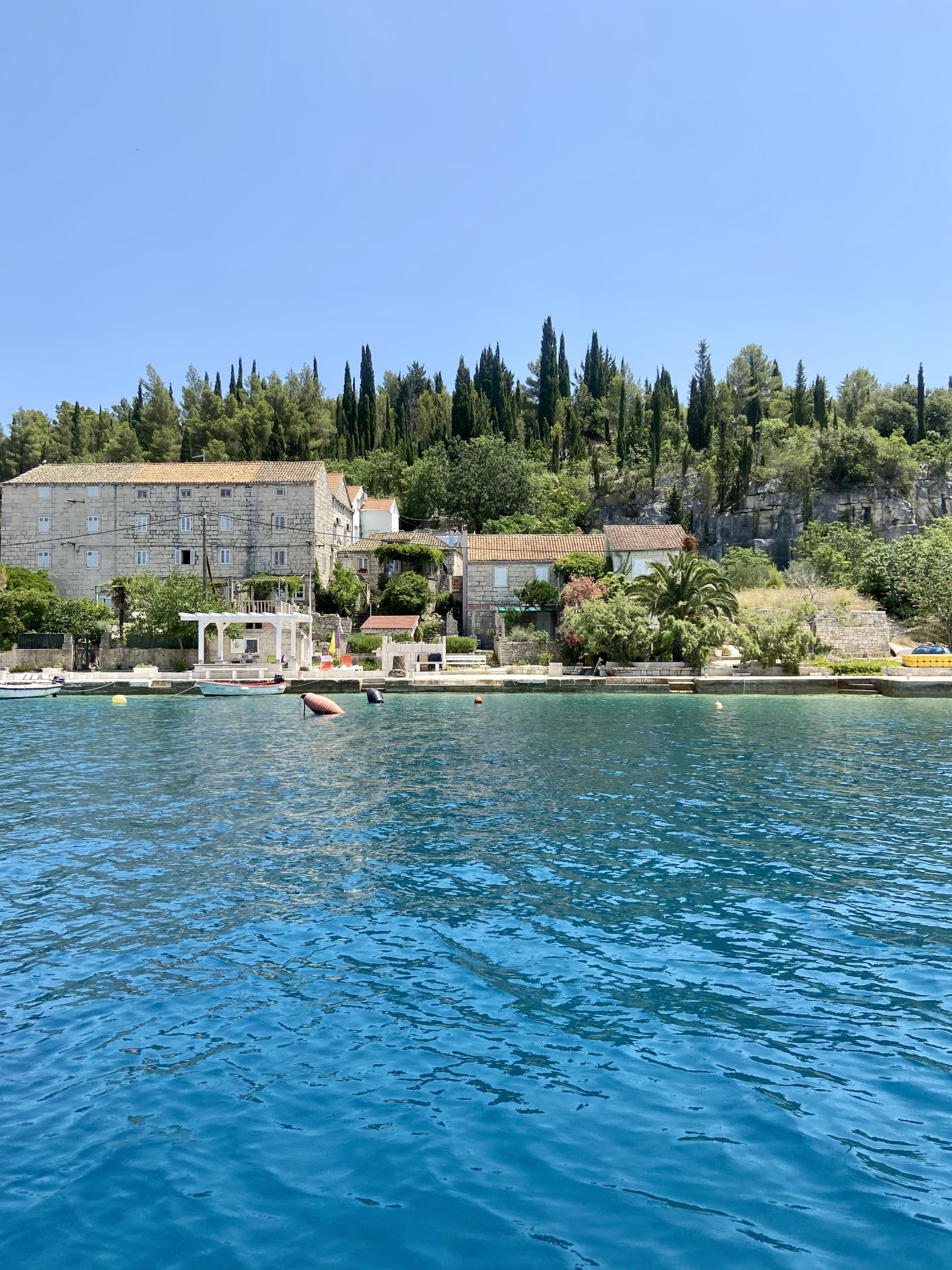 The image offers a peaceful waterfront scene, blending architecture and nature under a clear blue sky.