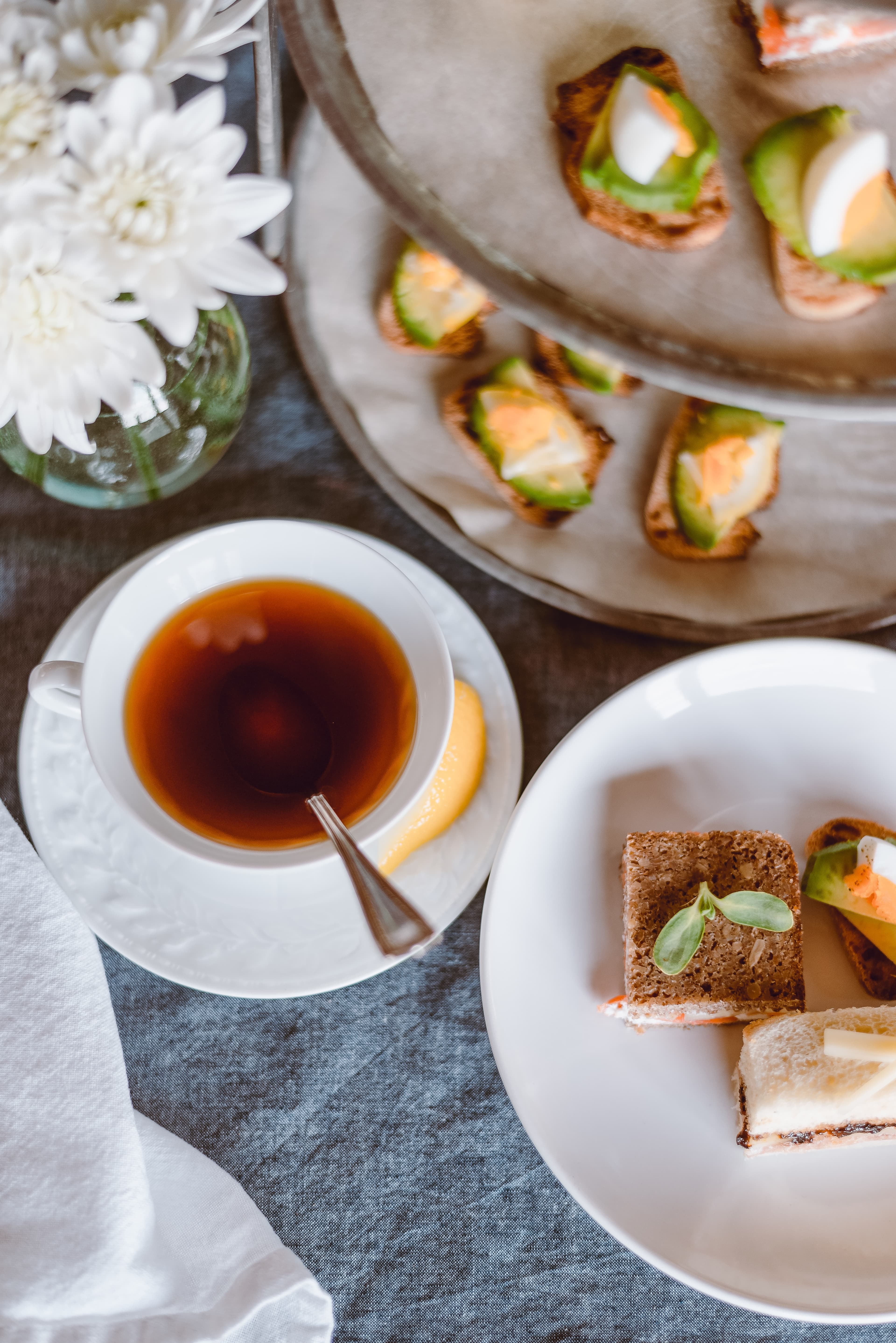 Afternoon tea featuring finger sandwiches, biscuits and black tea.