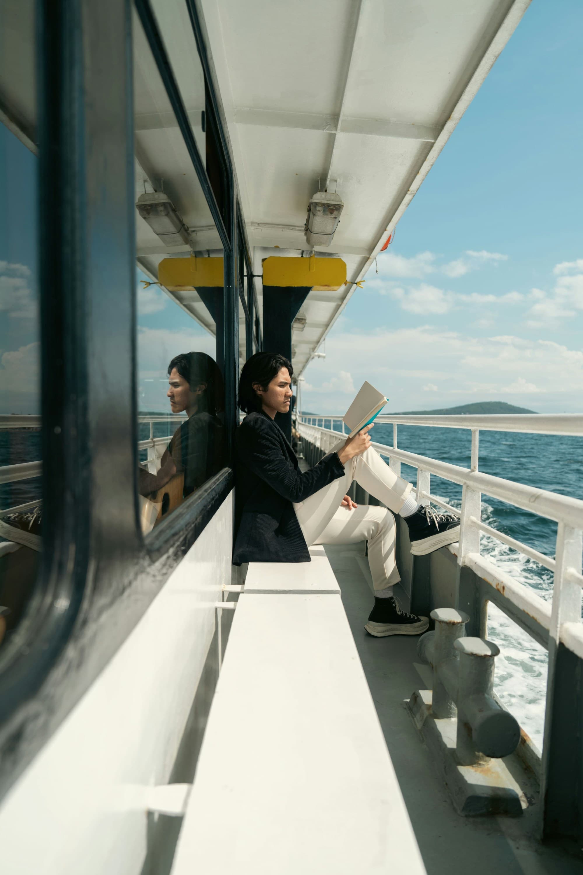 The image portrays a person enjoying a book on a cruise bench, with a serene sea view through the windows.