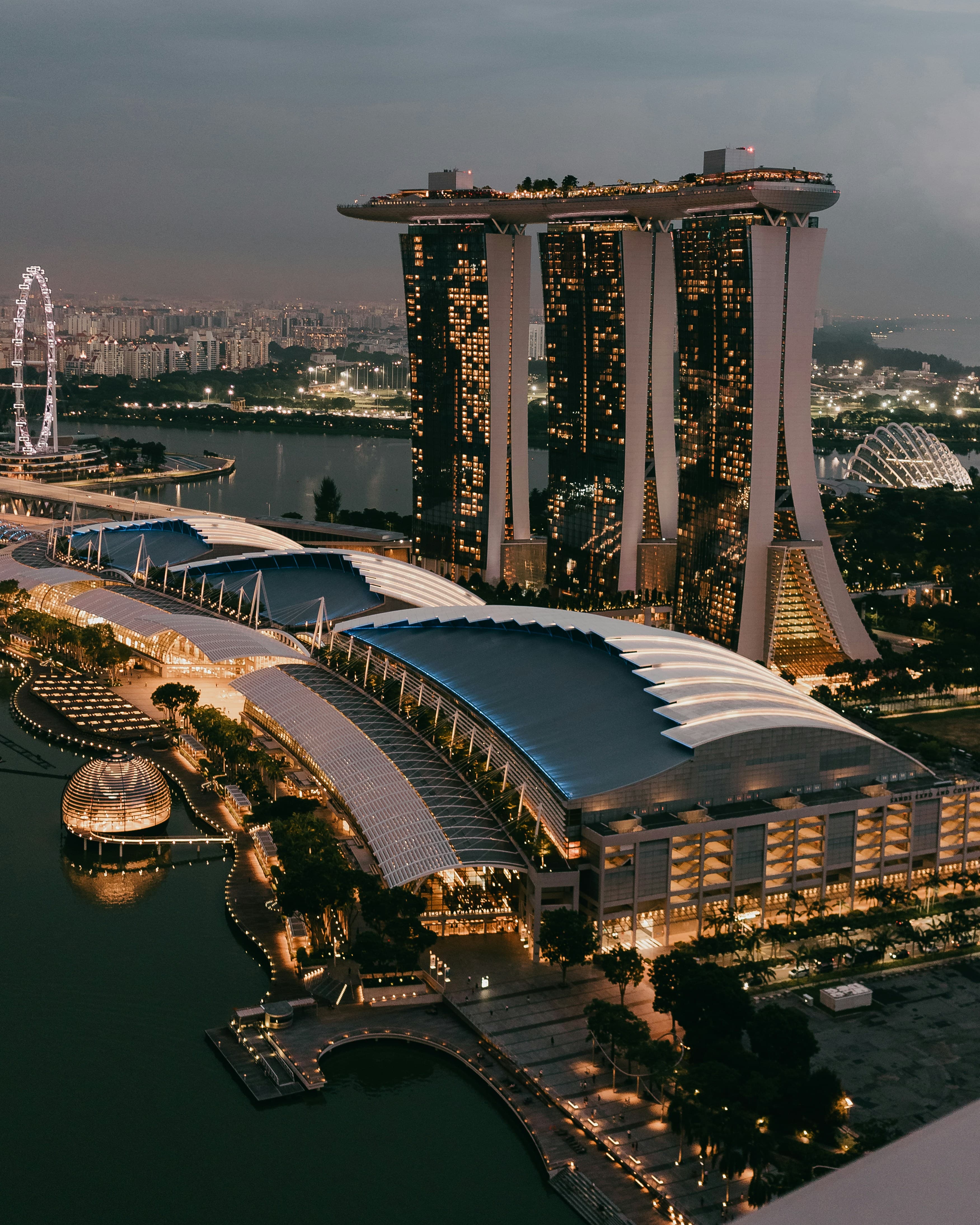 The Singapore skyline, highlighting the Marina Bay skyscraper, lit up at dusk.