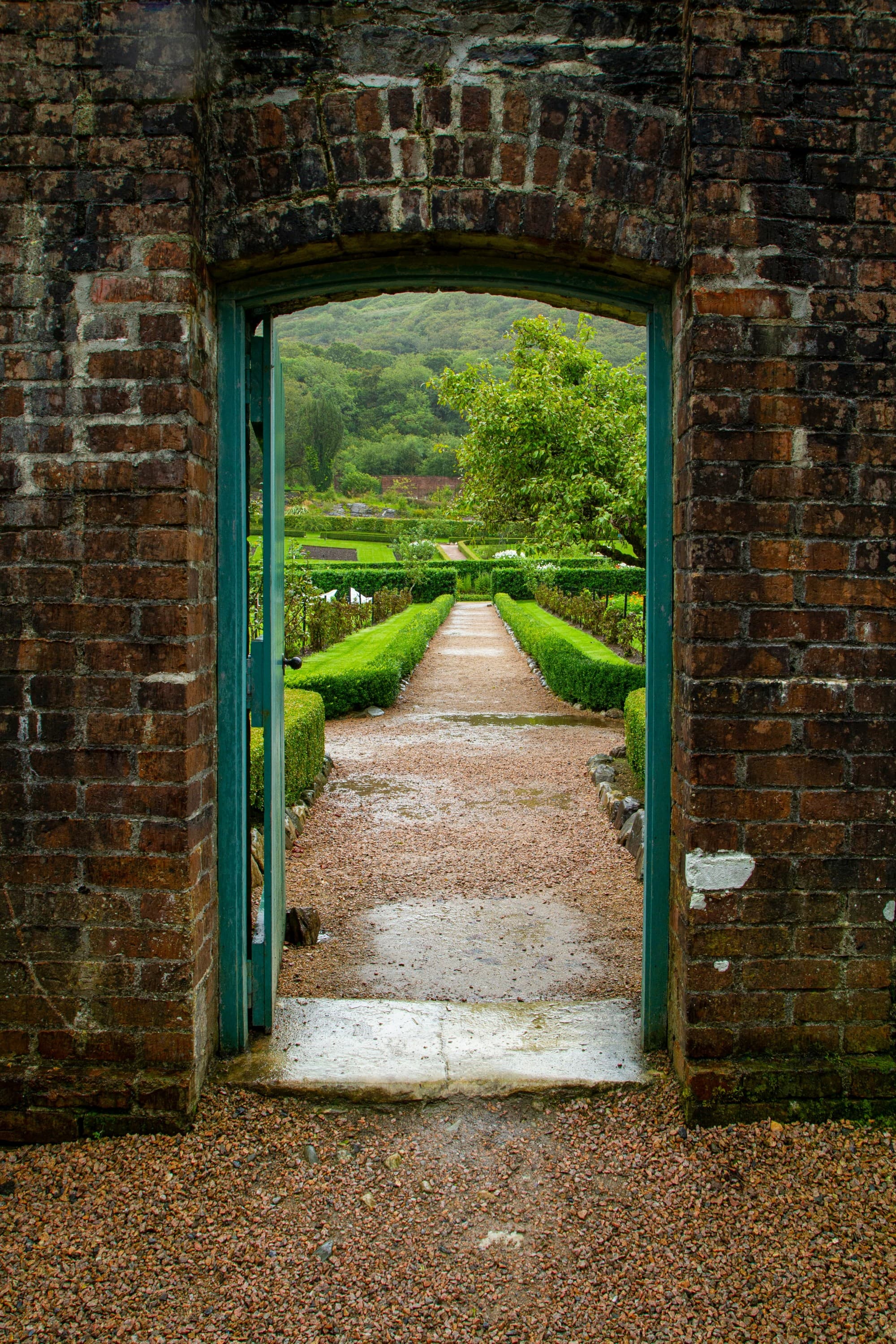 Brown brick wall with green grass field visible through a door.