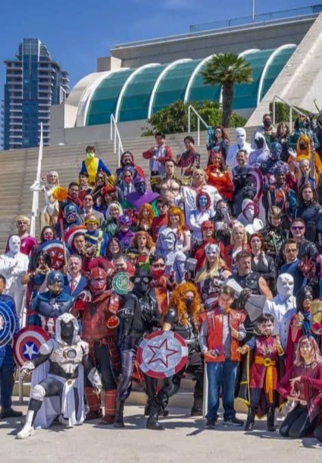A large group of people dressed in different comic characters posing for a group photo outside